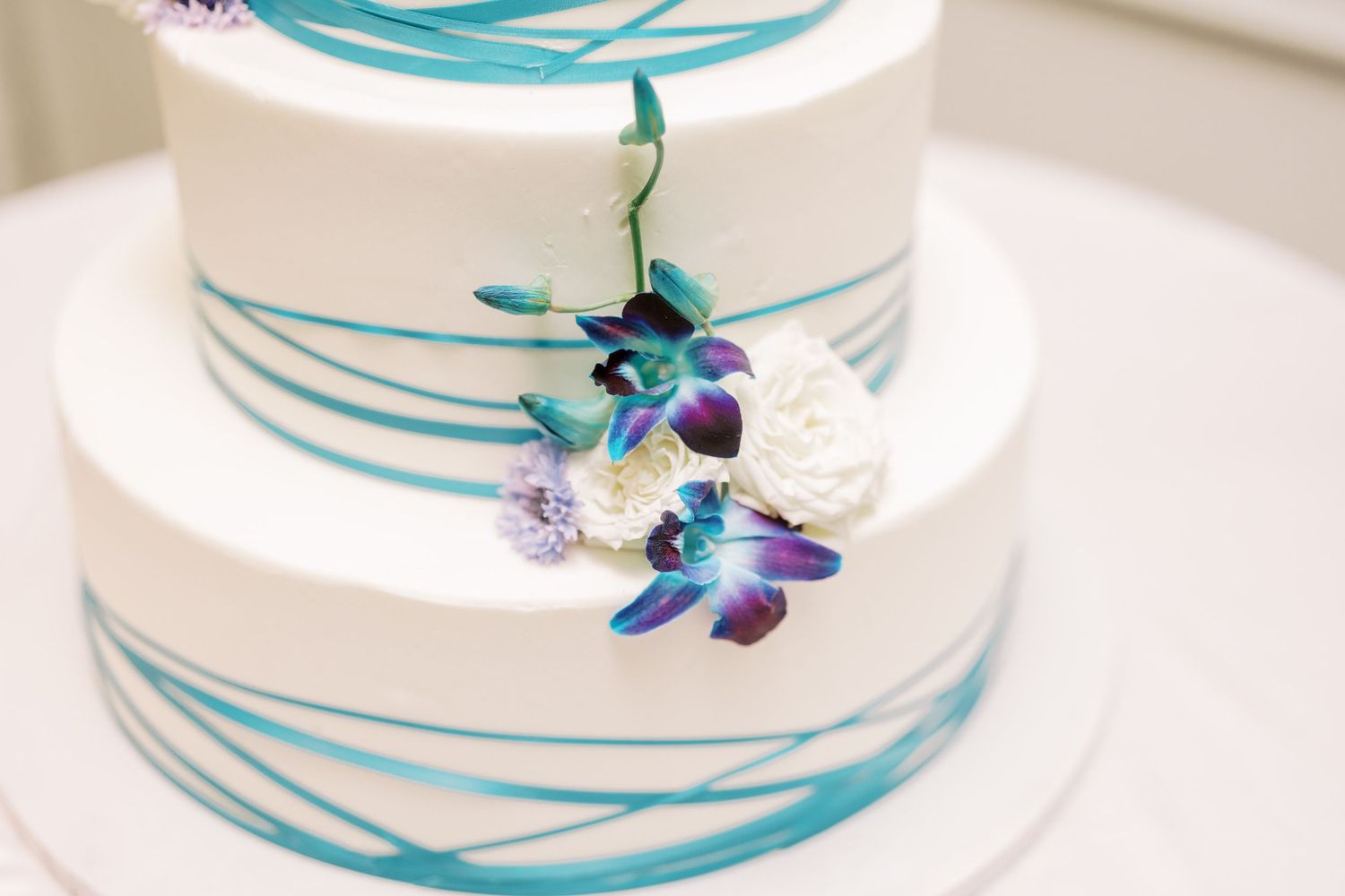 White cake with turquoise swirls decorated with a delicate purple and blue butterfly accent.