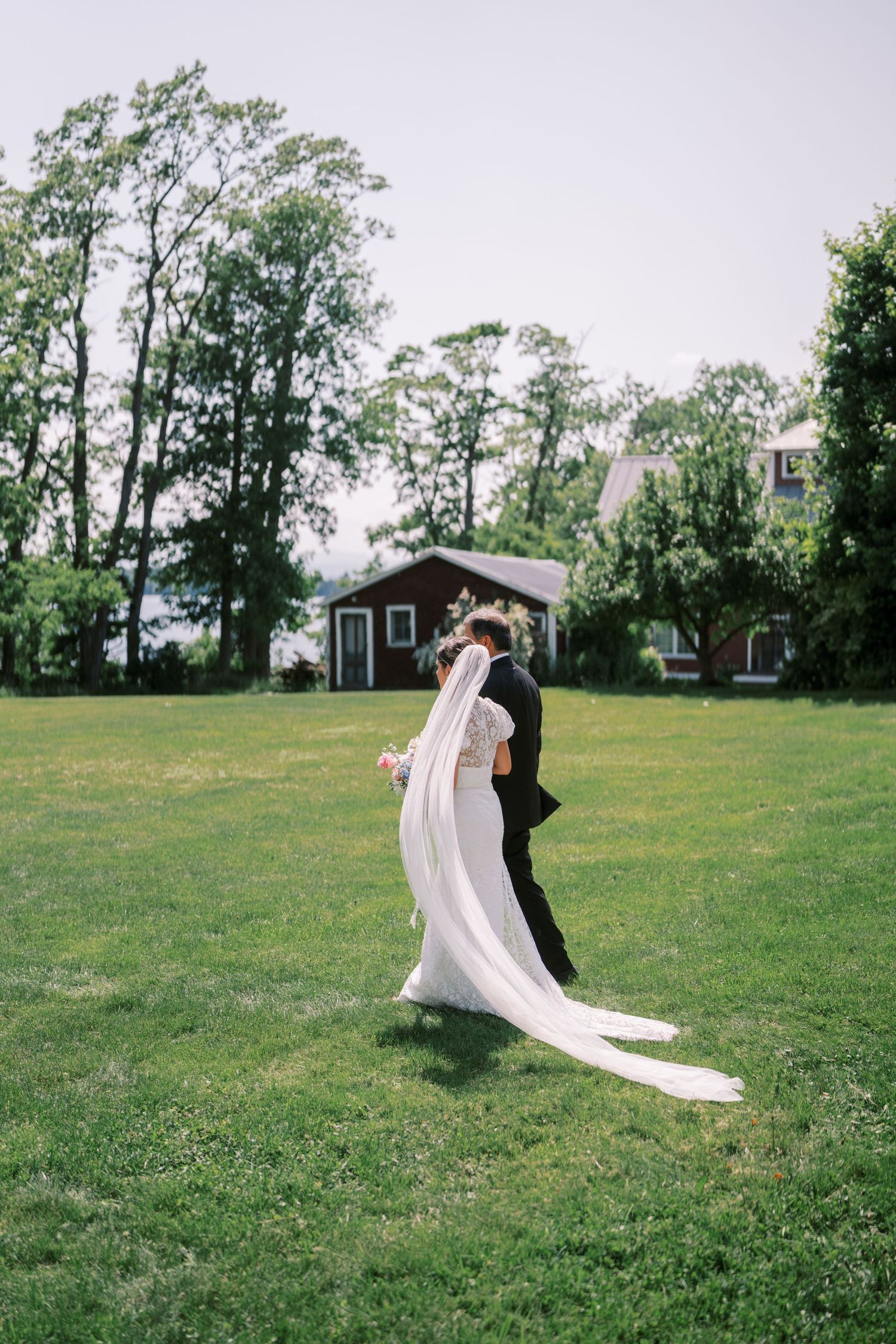 A flowing white veil dances in the wind across a lush green field on a summer day creating an elegant motion sequence.