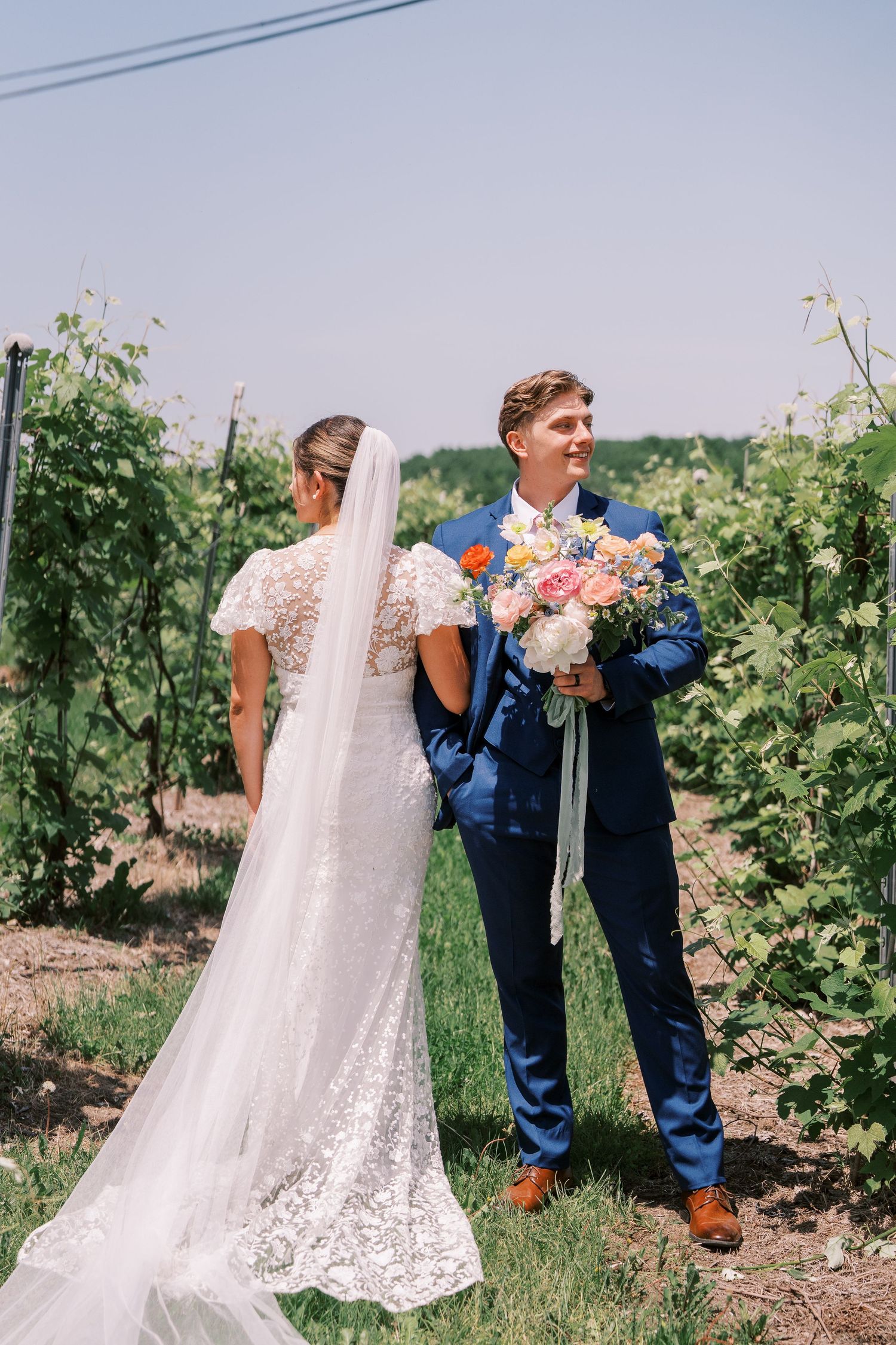 Five sequential wedding photos showing a couple sharing sweet playful moments between grapevines at a vineyard ceremony.