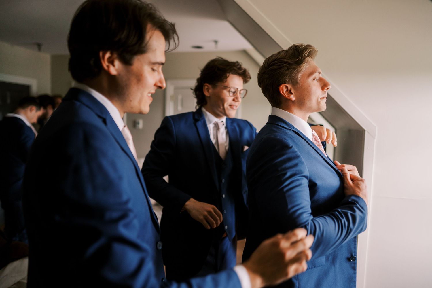 Several men wearing blue suits stand together in professional poses while preparing for a formal event.
