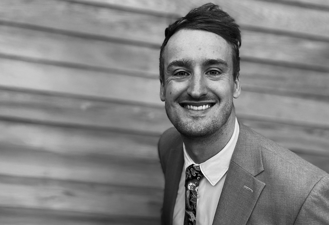 Black and white professional headshot portrait of Gregg wearing a suit and tie.