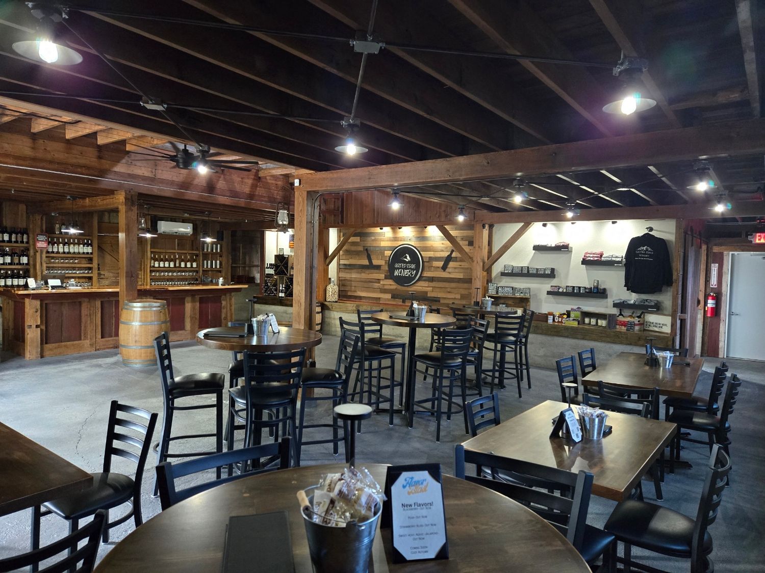 A rustic winery tasting room with wooden beams, bar seating, and tables arranged in an inviting atmosphere.