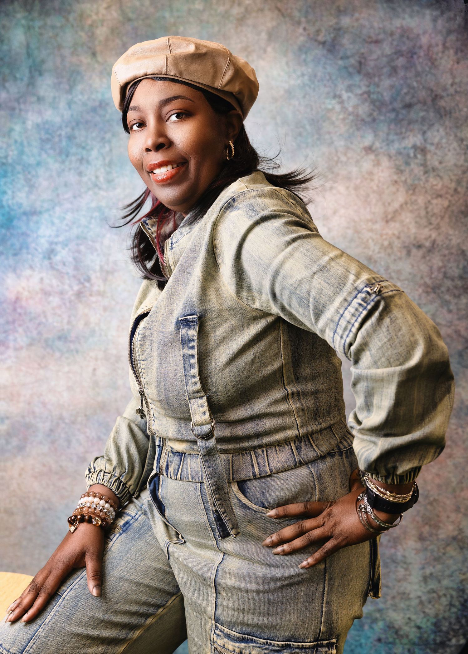 Fashion portrait of someone in trendy denim outfit with beige beret and layered denim against textured backdrop.