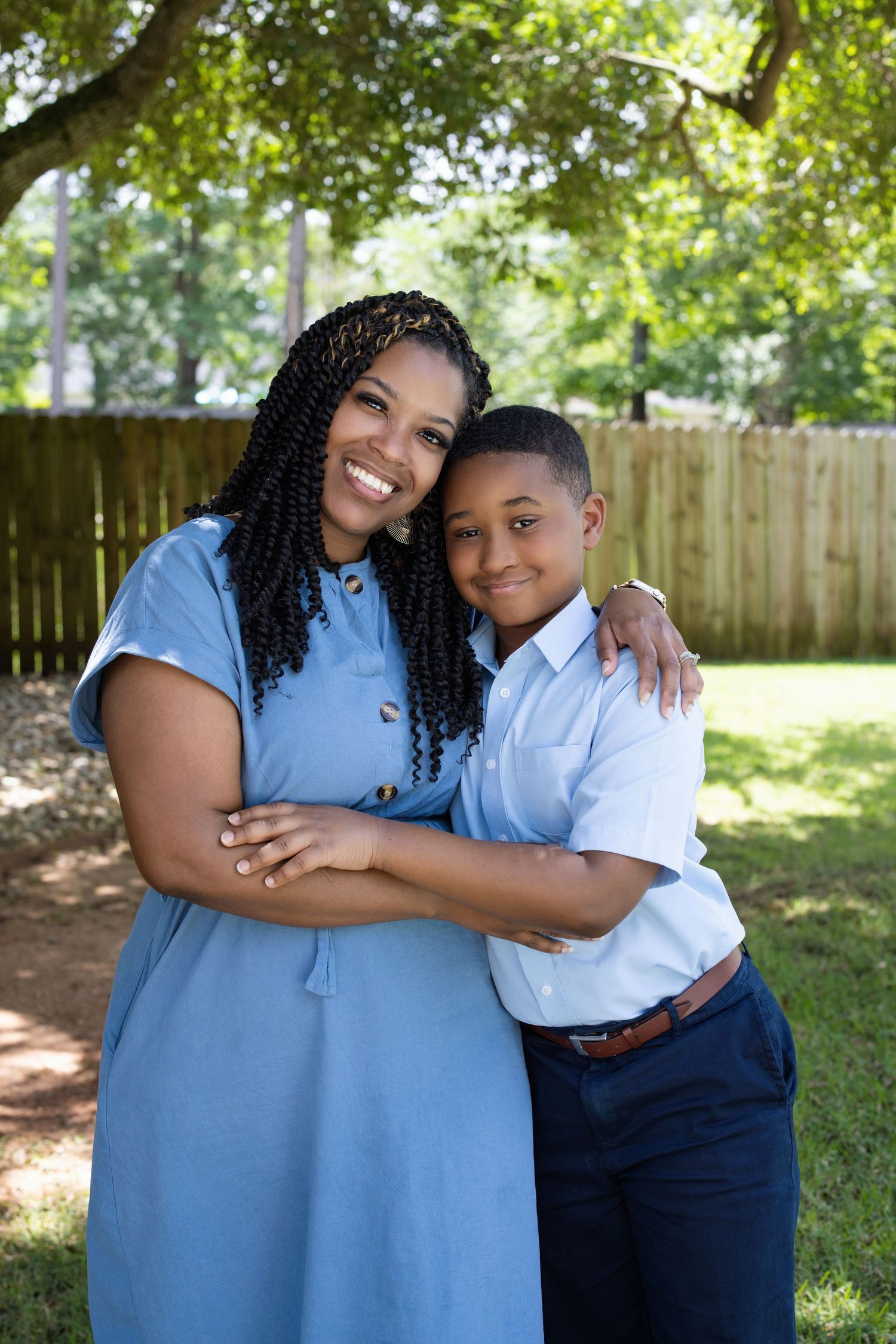 A touching outdoor portrait of parent and child embracing in a sunlit backyard.