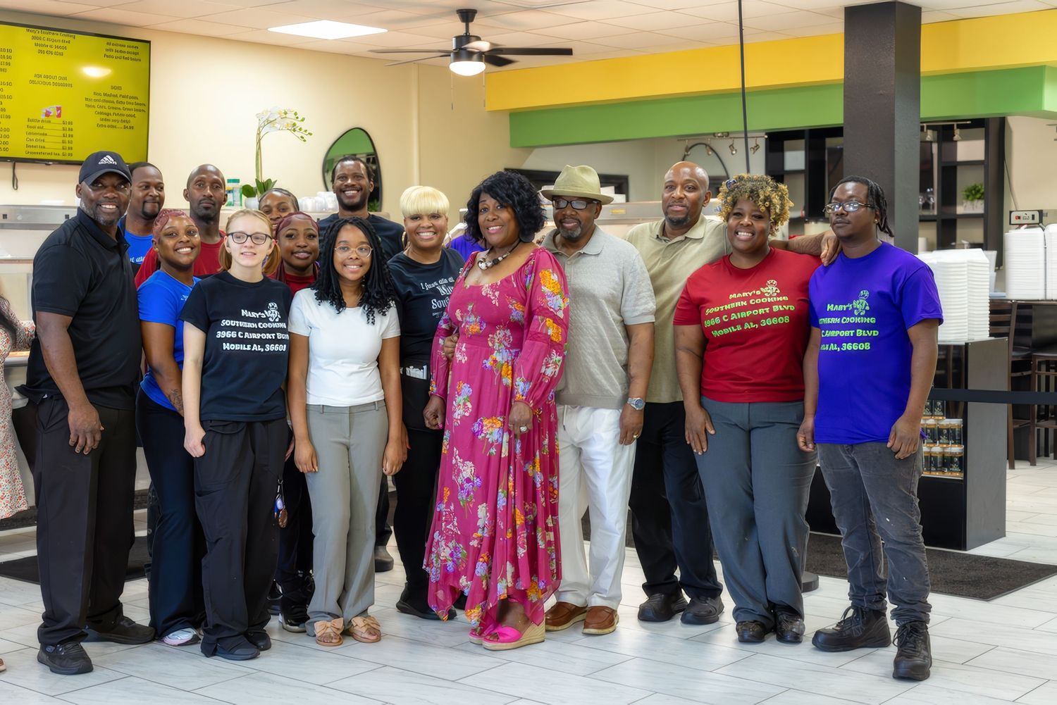 A group of people stand together smiling inside a retail store with yellow and green walls and bright lighting.