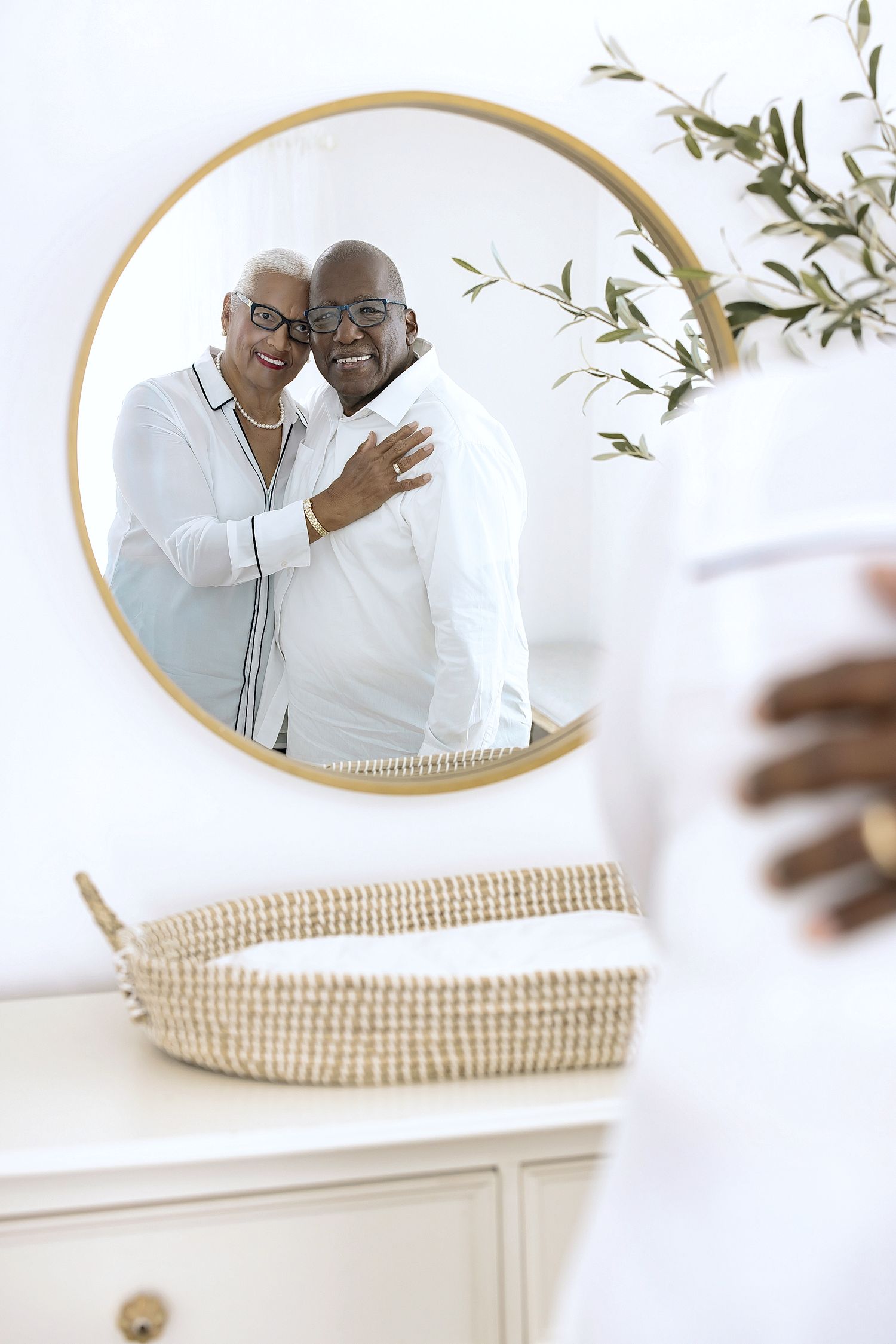 A woven basket sits below an oval mirror mounted on a white wall, creating a minimalist home decor arrangement.