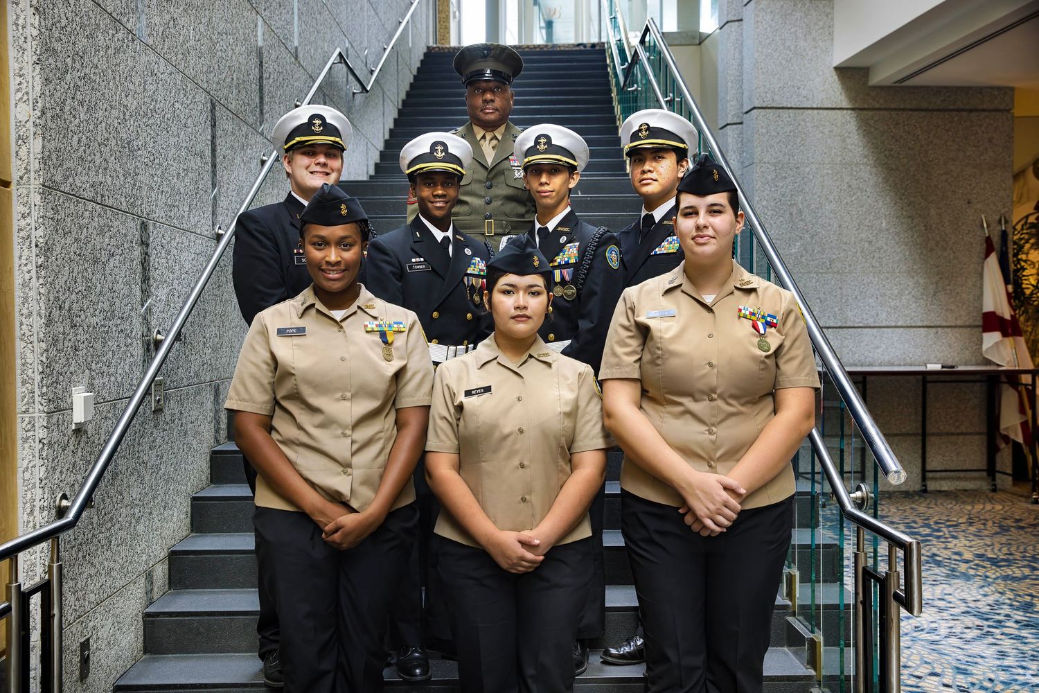 Military or naval personnel in uniforms posed on stairs for group photo.