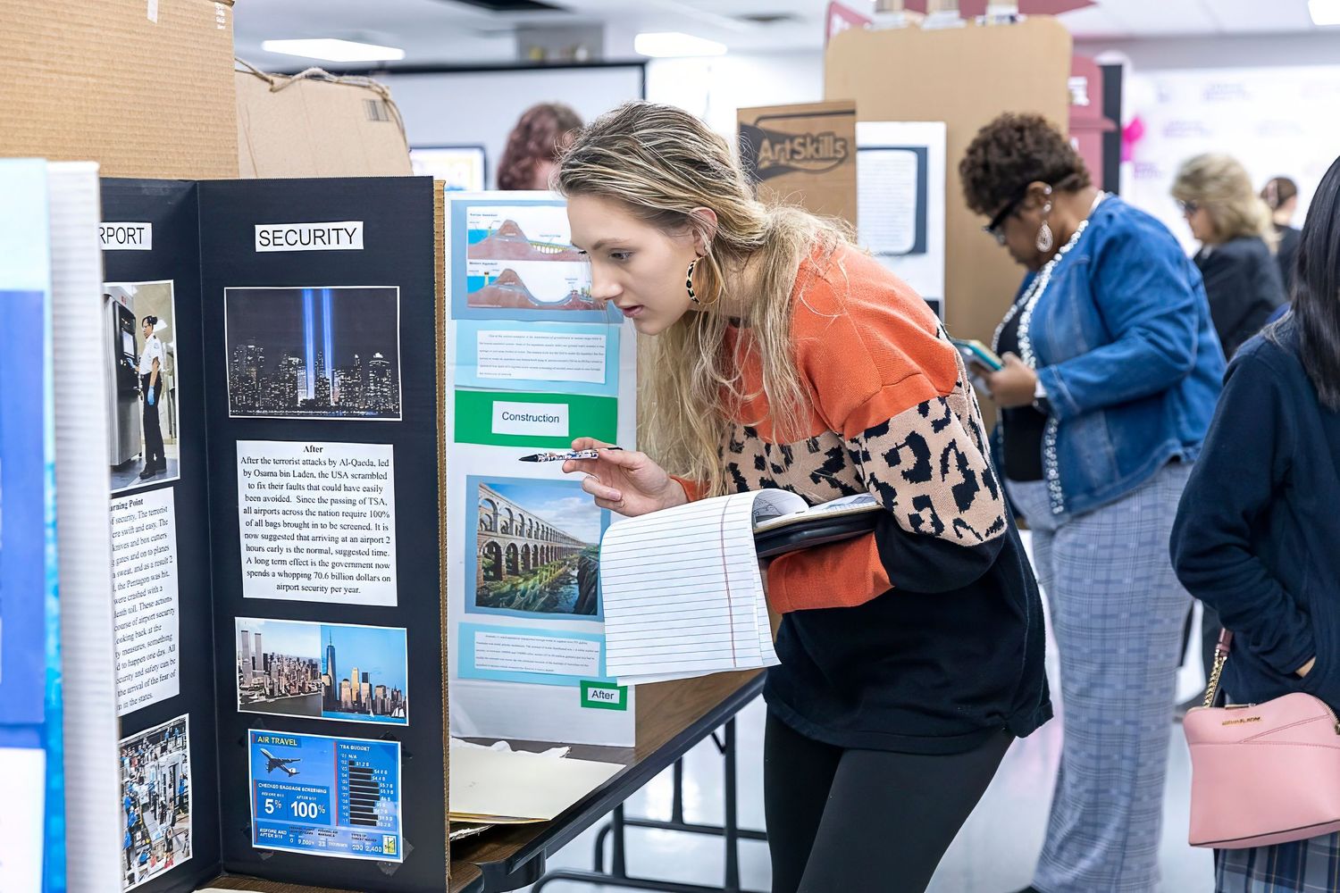 Student examining display boards at a school fair or exhibition.