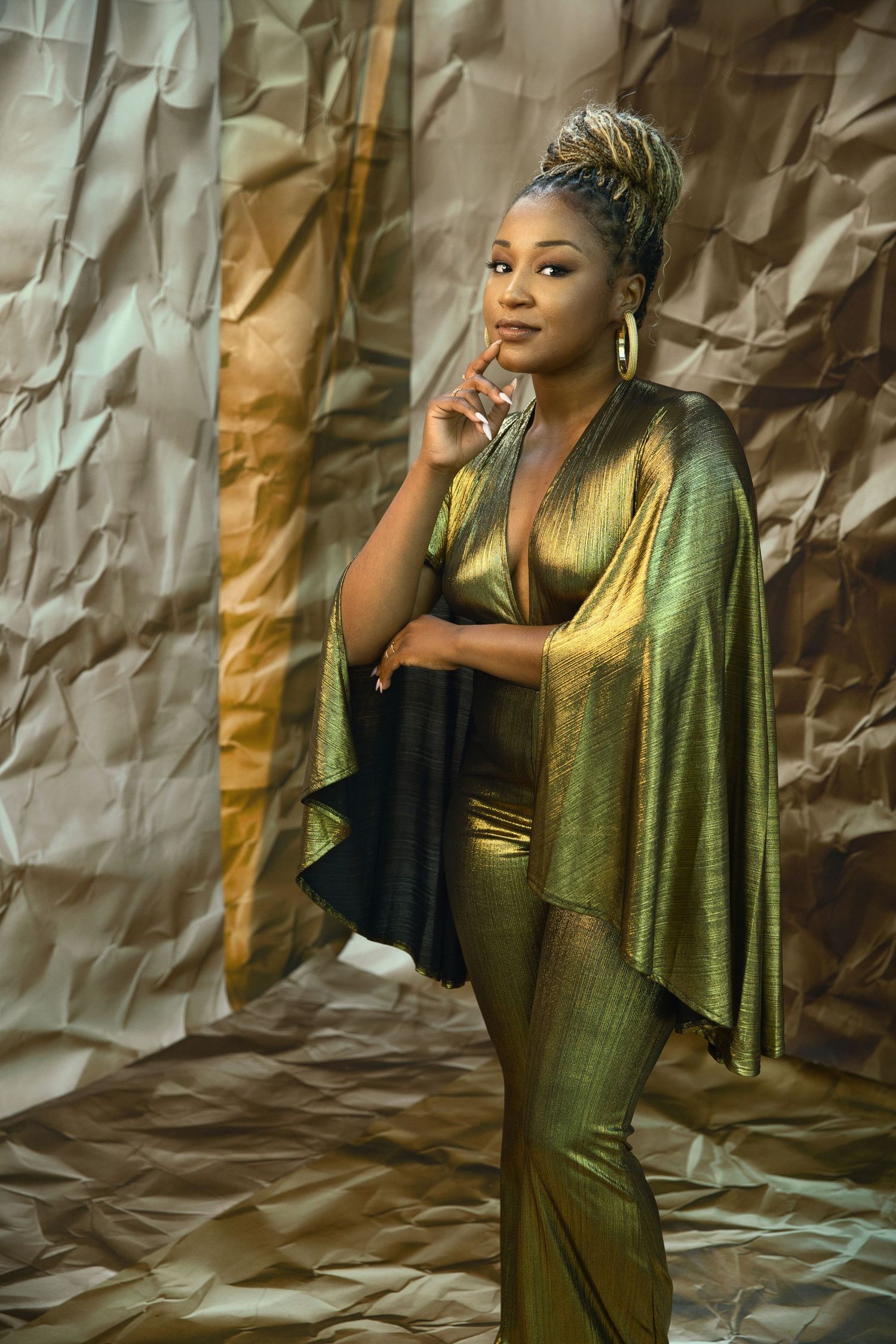 Elegant portrait in metallic green ensemble against textured gold backdrop.