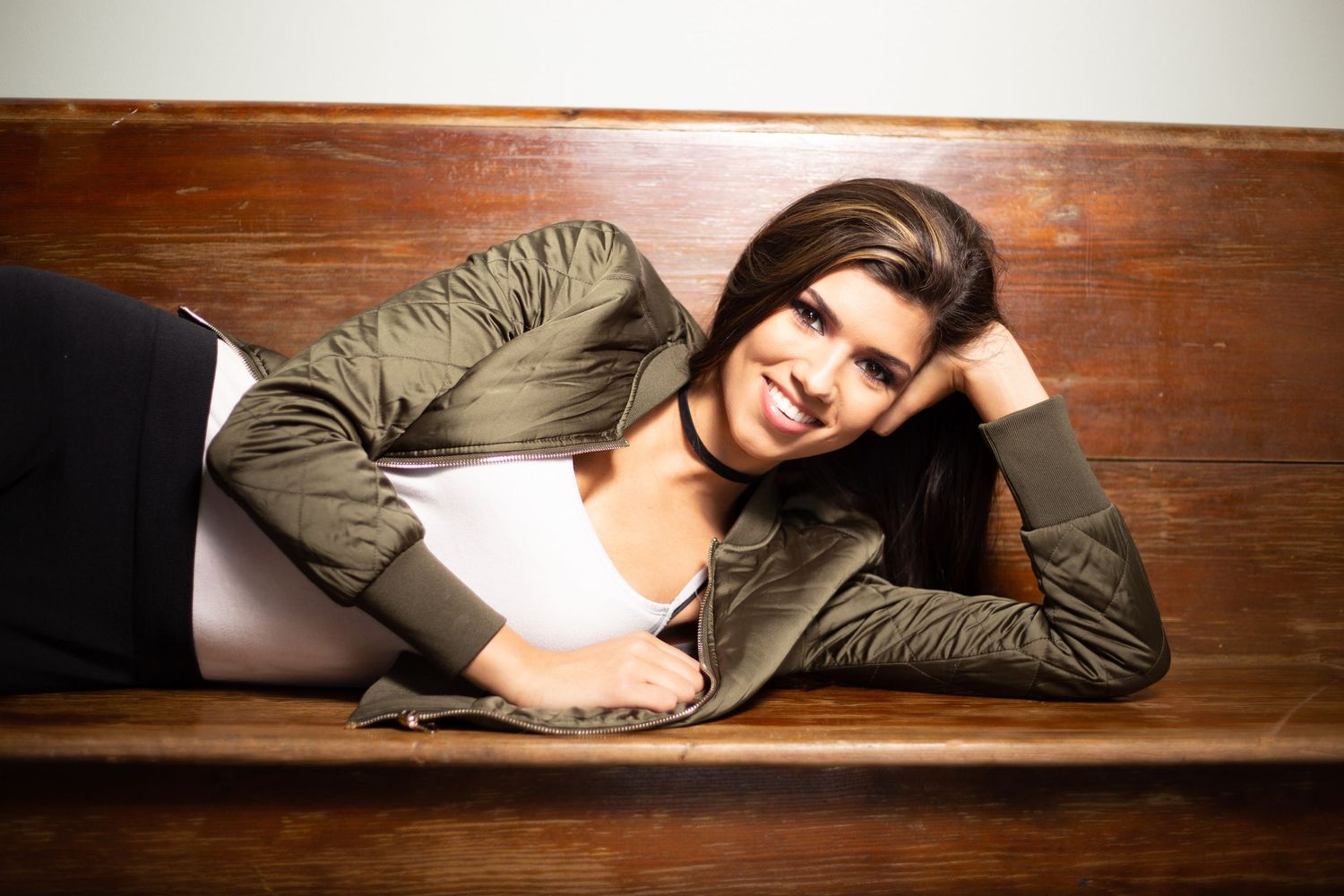 Model in casual attire lying on wooden surface during professional photoshoot.