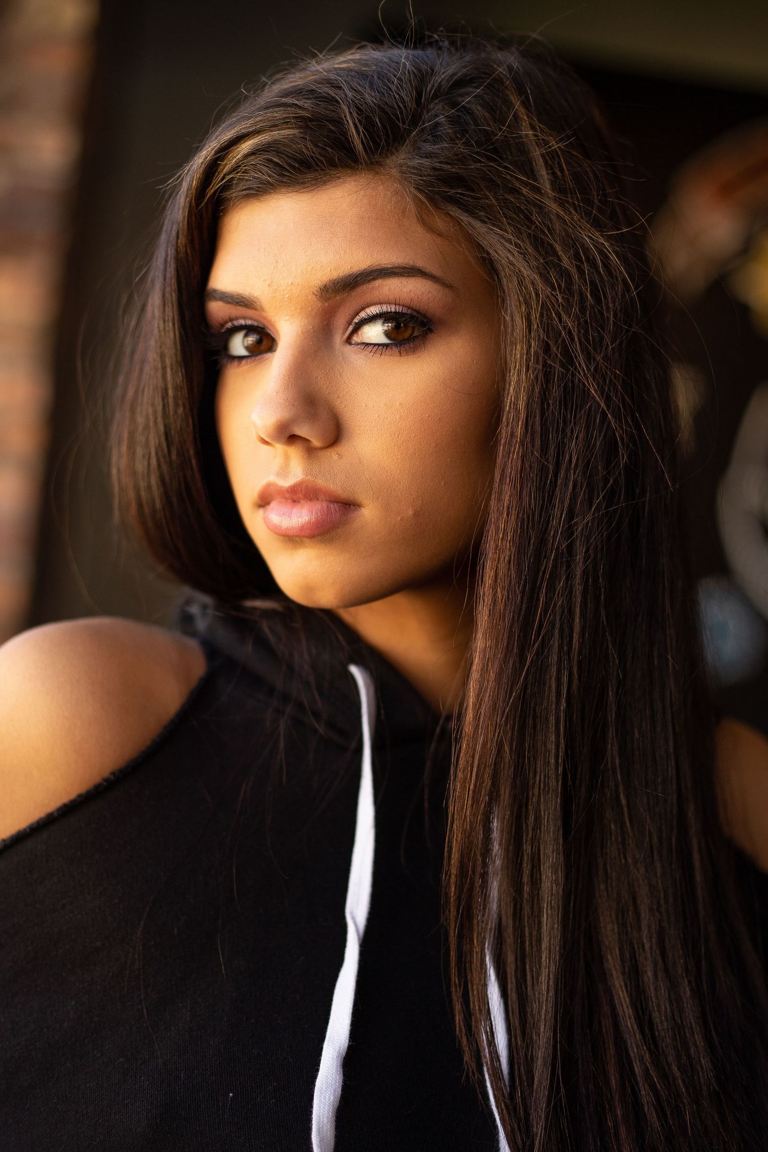 Dramatic portrait featuring long dark hair and professional makeup in studio lighting.