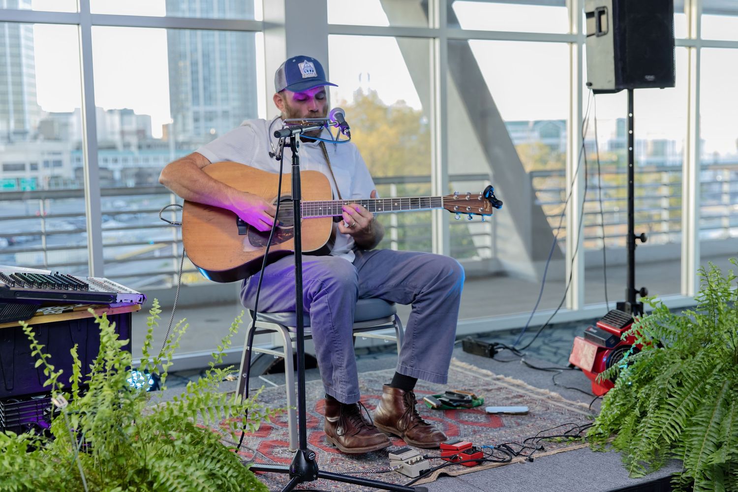 Musicians perform on an outdoor rooftop venue with city skyline visible in the background.