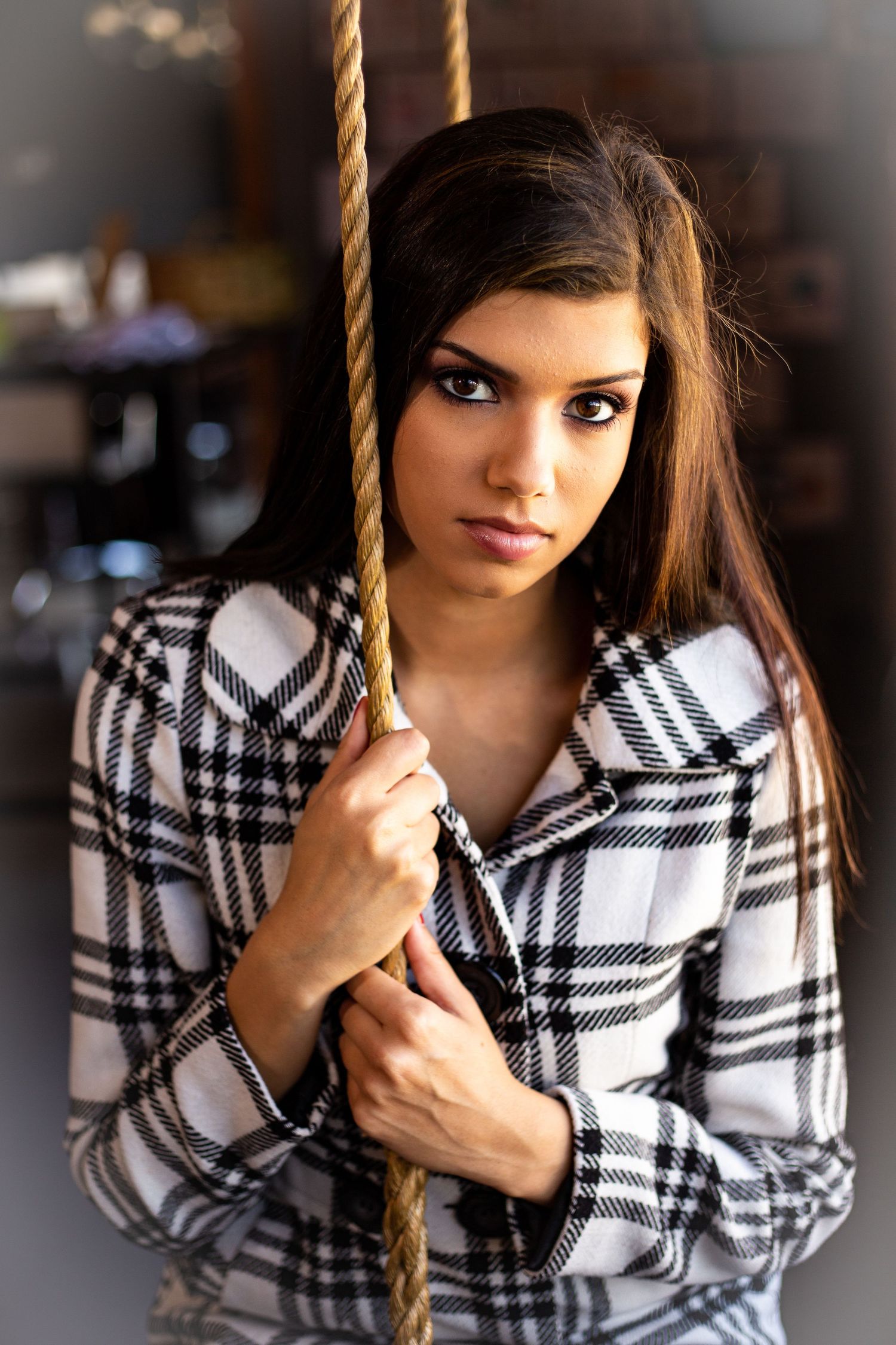 Fashion portrait of model in black and white plaid shirt holding rope swing.