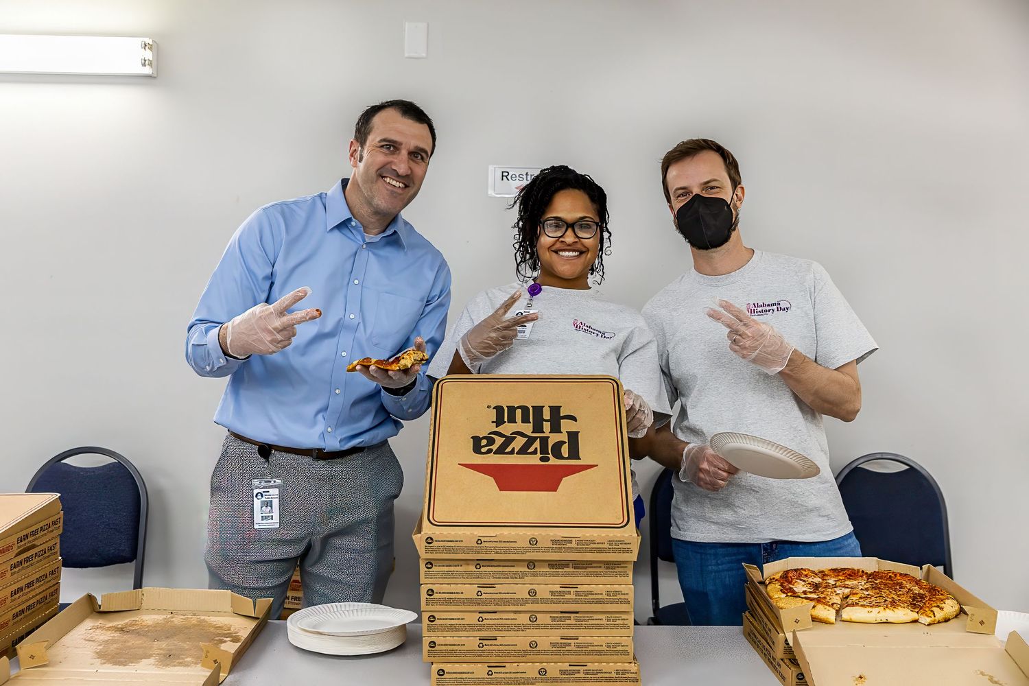Three people posing with pizza boxes during corporate event