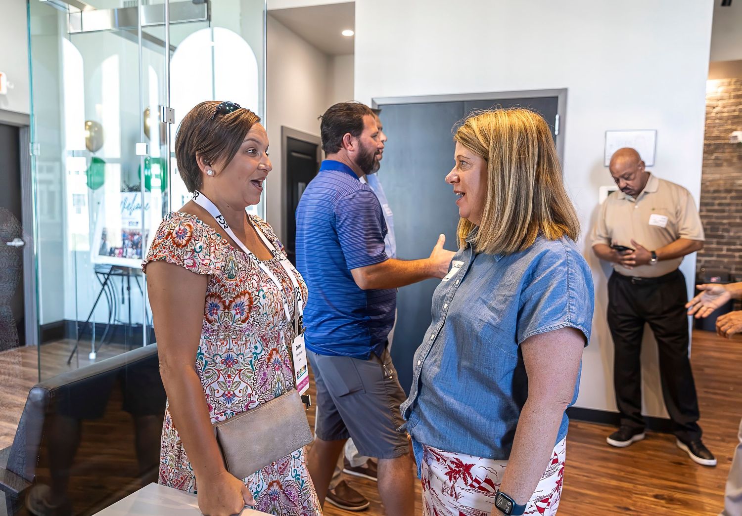People networking and having conversations at a modern office space with exposed brick walls.
