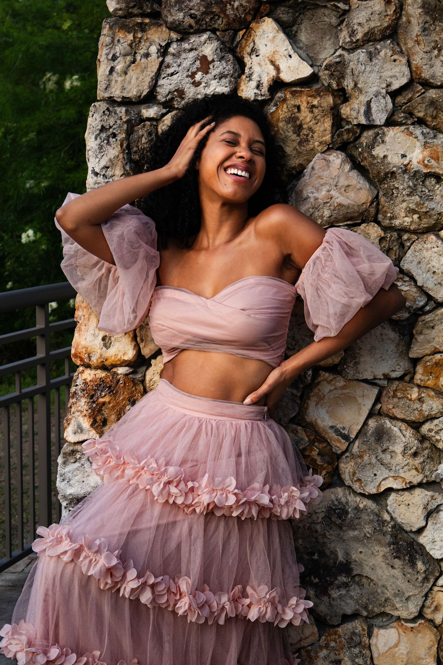 Pexels event with AMirraofAmira photography, capturing a fair skinned women in a beautiful pink ruffled dress against a brick wall
