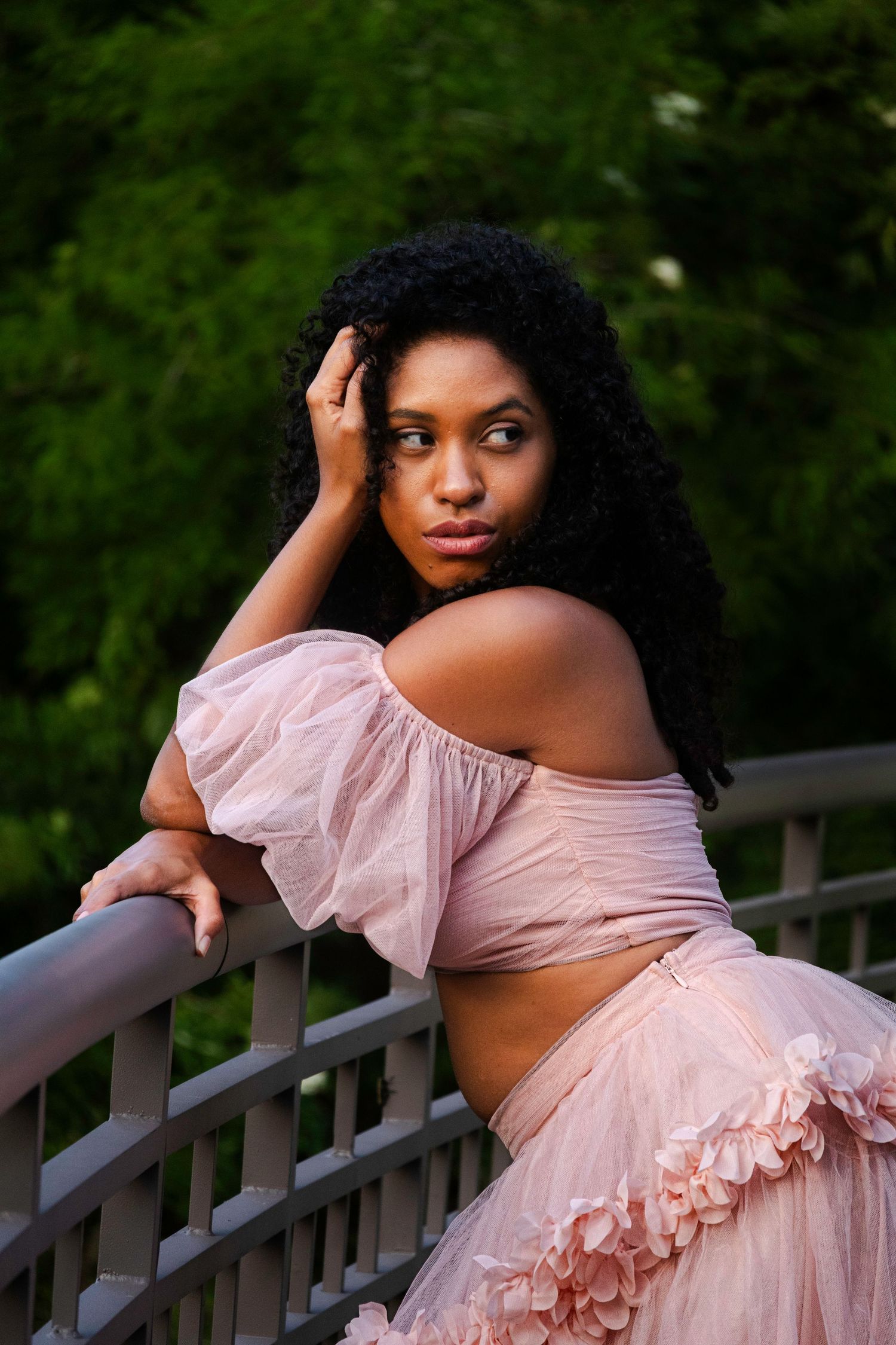 Pexels event with AMirraofAmira photography, capturing a fair skinned women in a beautiful pink ruffled dress leaning against a railing