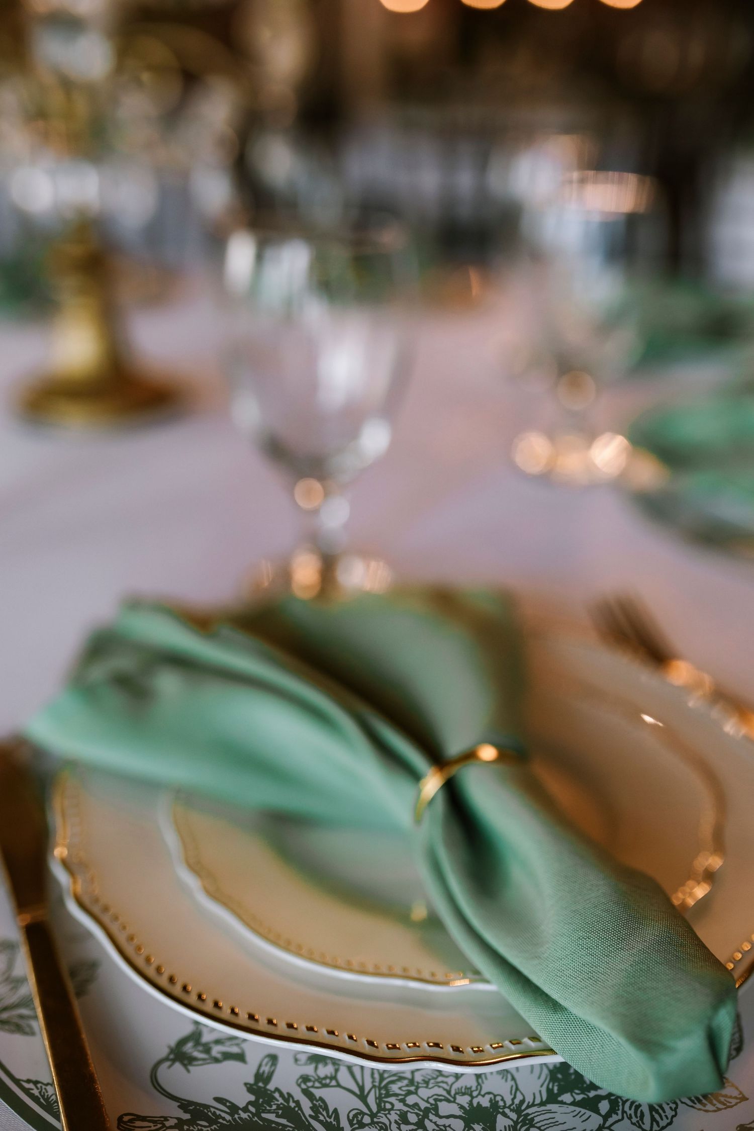 Elegant table setting with mint green napkins and white plates in soft lighting for an upscale dining event.