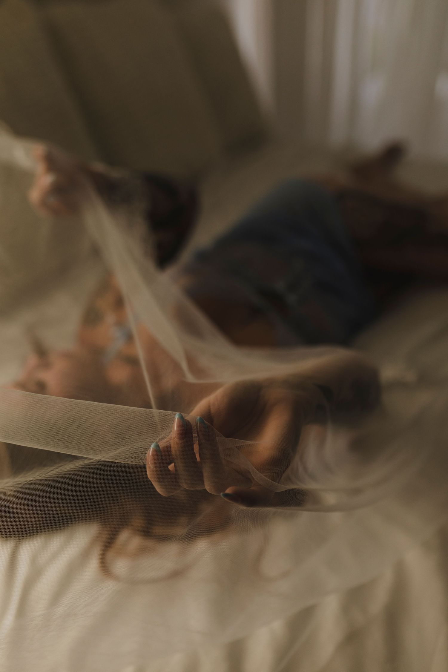 A hand holding a book emerges through ethereal smoke in a moody, atmospheric indoor setting.