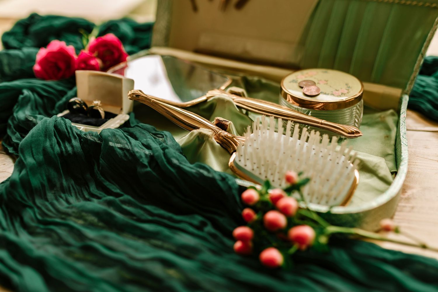 Holiday decor featuring red berries and eucalyptus arranged on dark green velvet fabric with vintage style details.