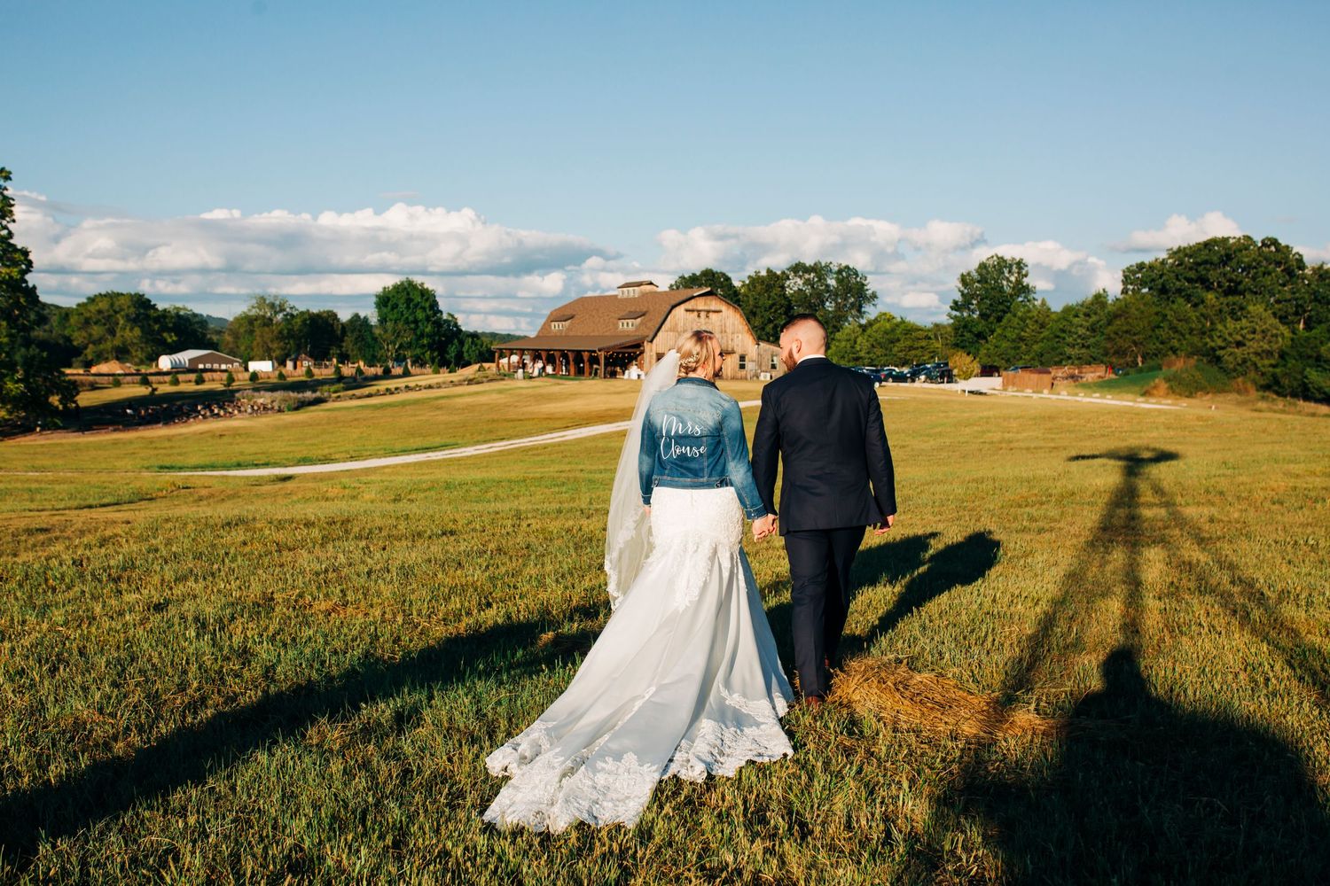 Bride and groom walk away  wardsSycamore Ranch in Branson Missouri with dramatic shadows in golden sunlight.