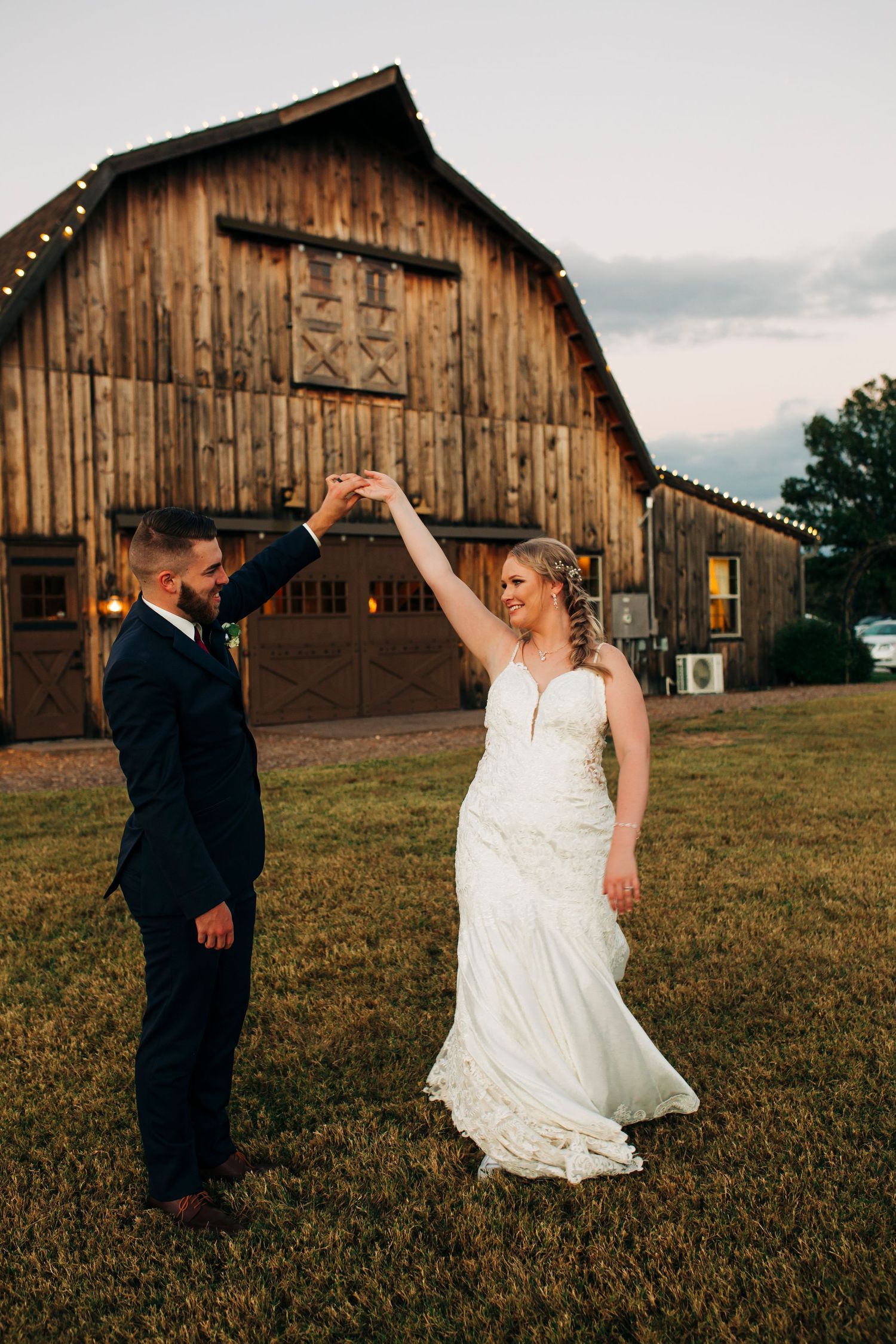 Groom twirls bride in elegant white dress outside Sycamore Ranch in Branson Missouri.