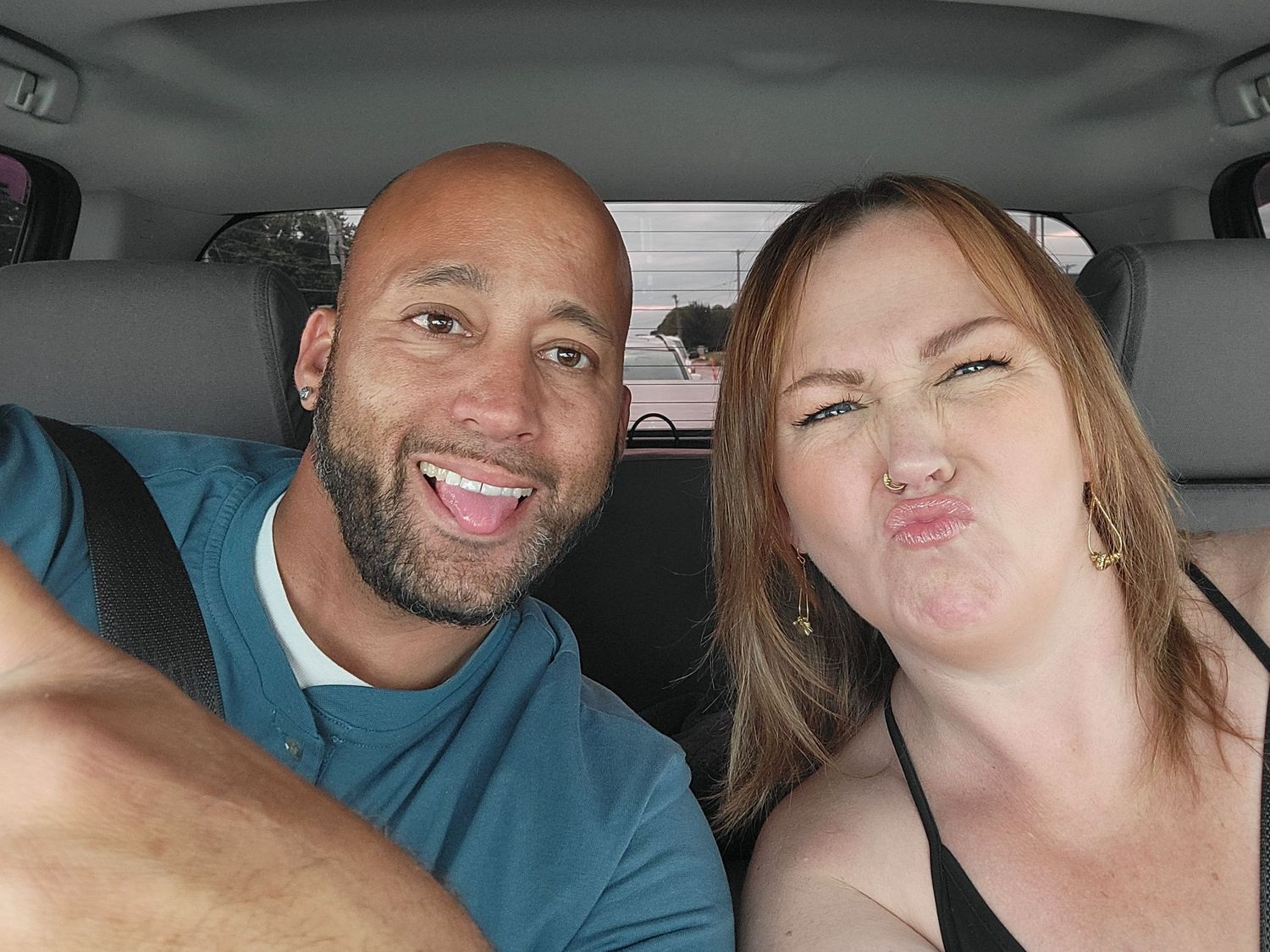 Two people taking a series of playful selfies together in a car.