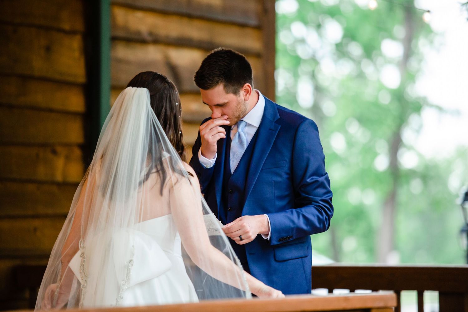 Emotional first look between couple on rustic cabin porch.