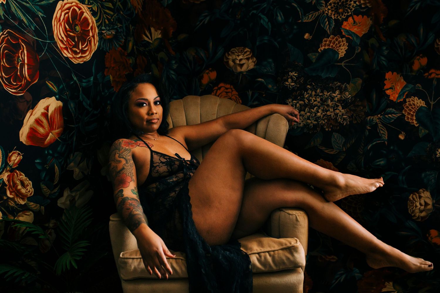 Woman in black lace lingerie seated on velvet chair in Republic MO boudoir studio.