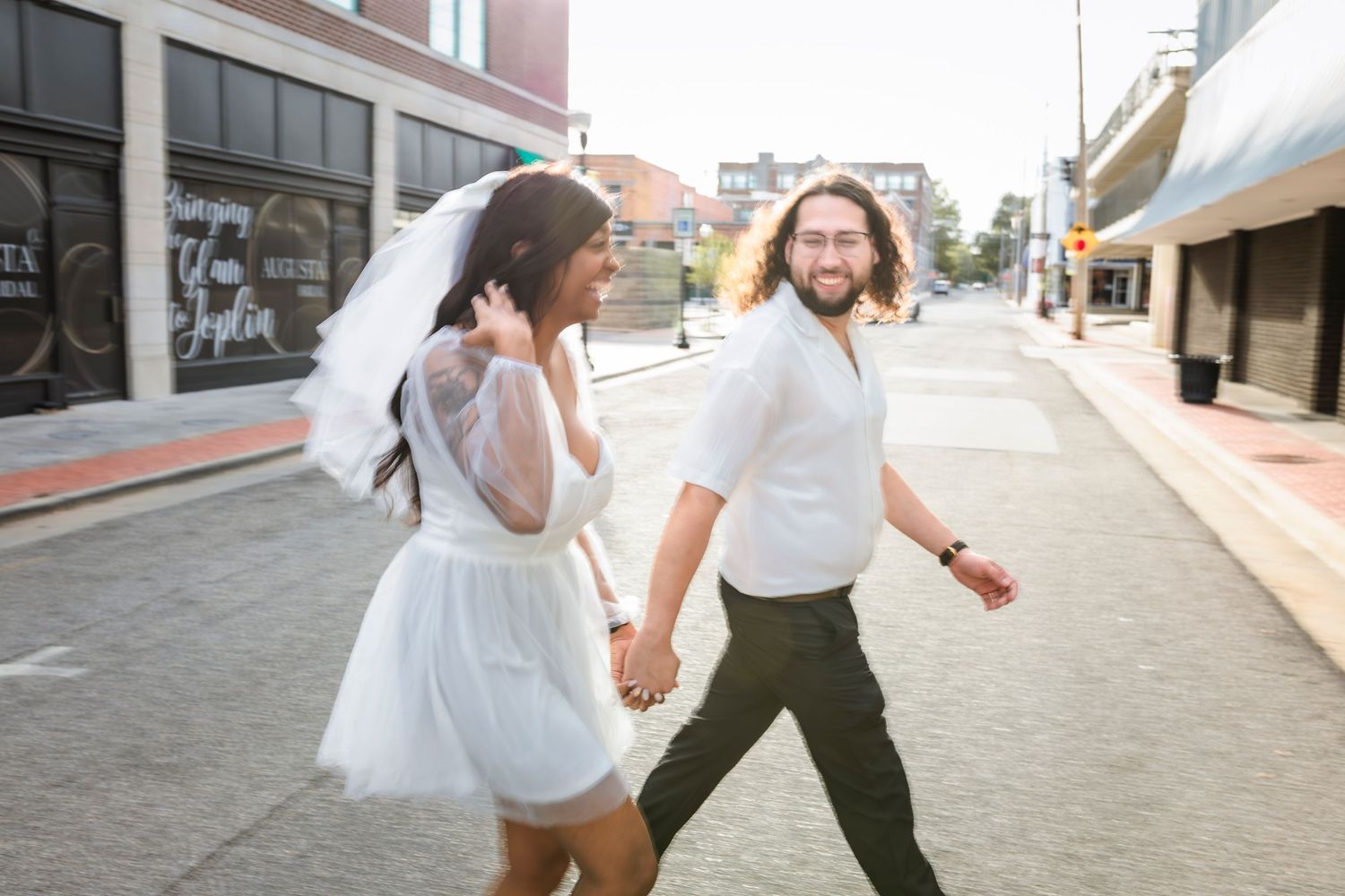 A happy wedding couple walking hand in hand down overlapping train tracks.