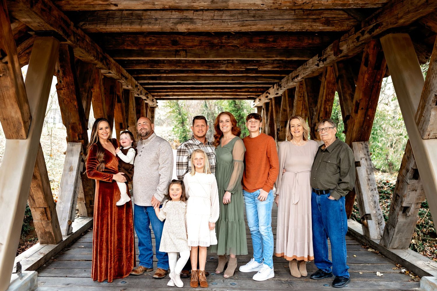 A panoramic group shot of people standing inside a rustic wooden covered bridge interior.