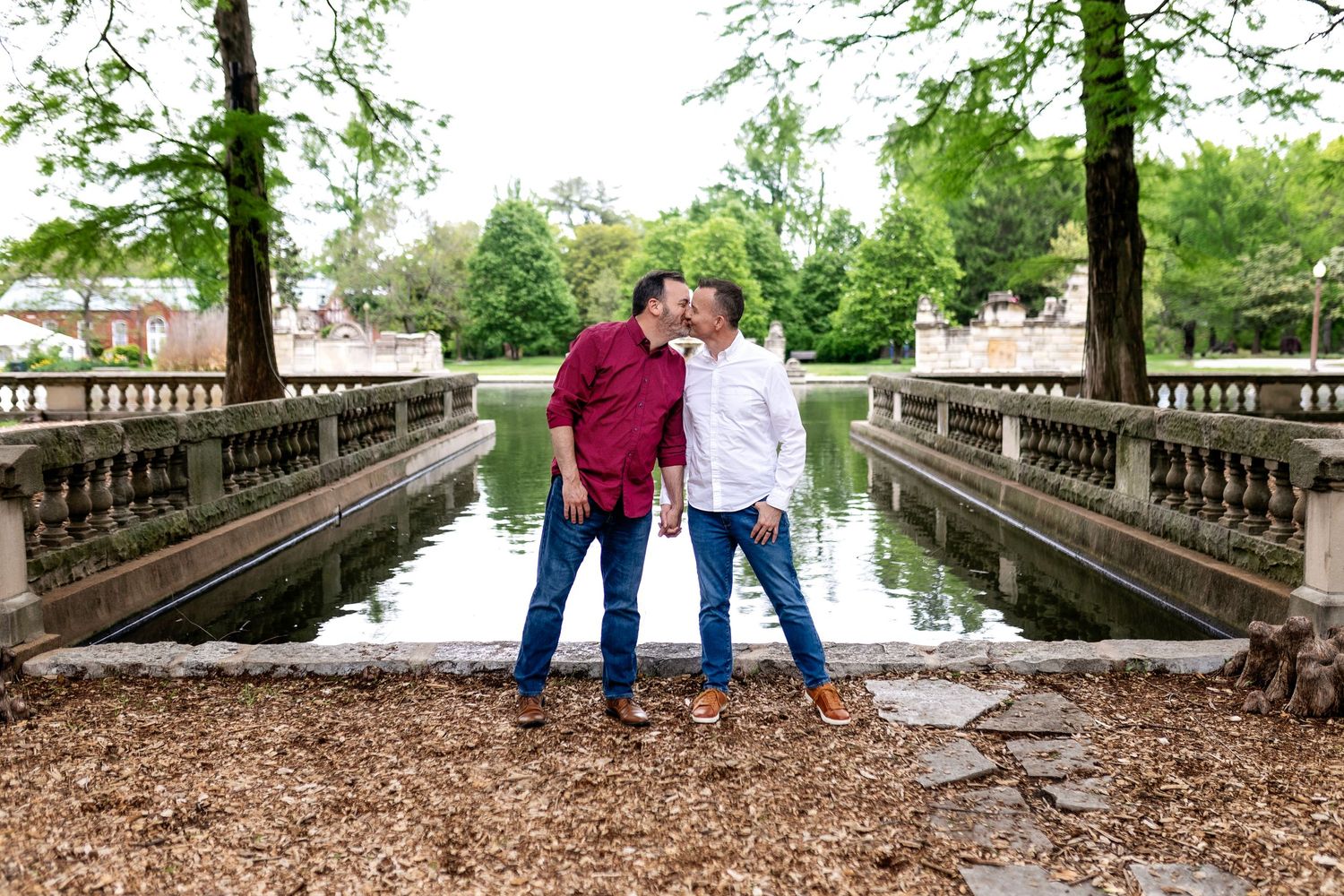 Couple posing together in St. Louis MO on stone bridge in park setting.