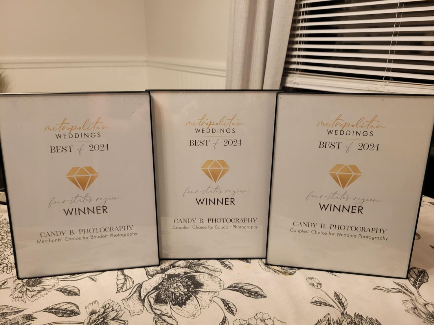 Three silver wedding awards with gold diamond icons displayed on a floral patterned surface.
