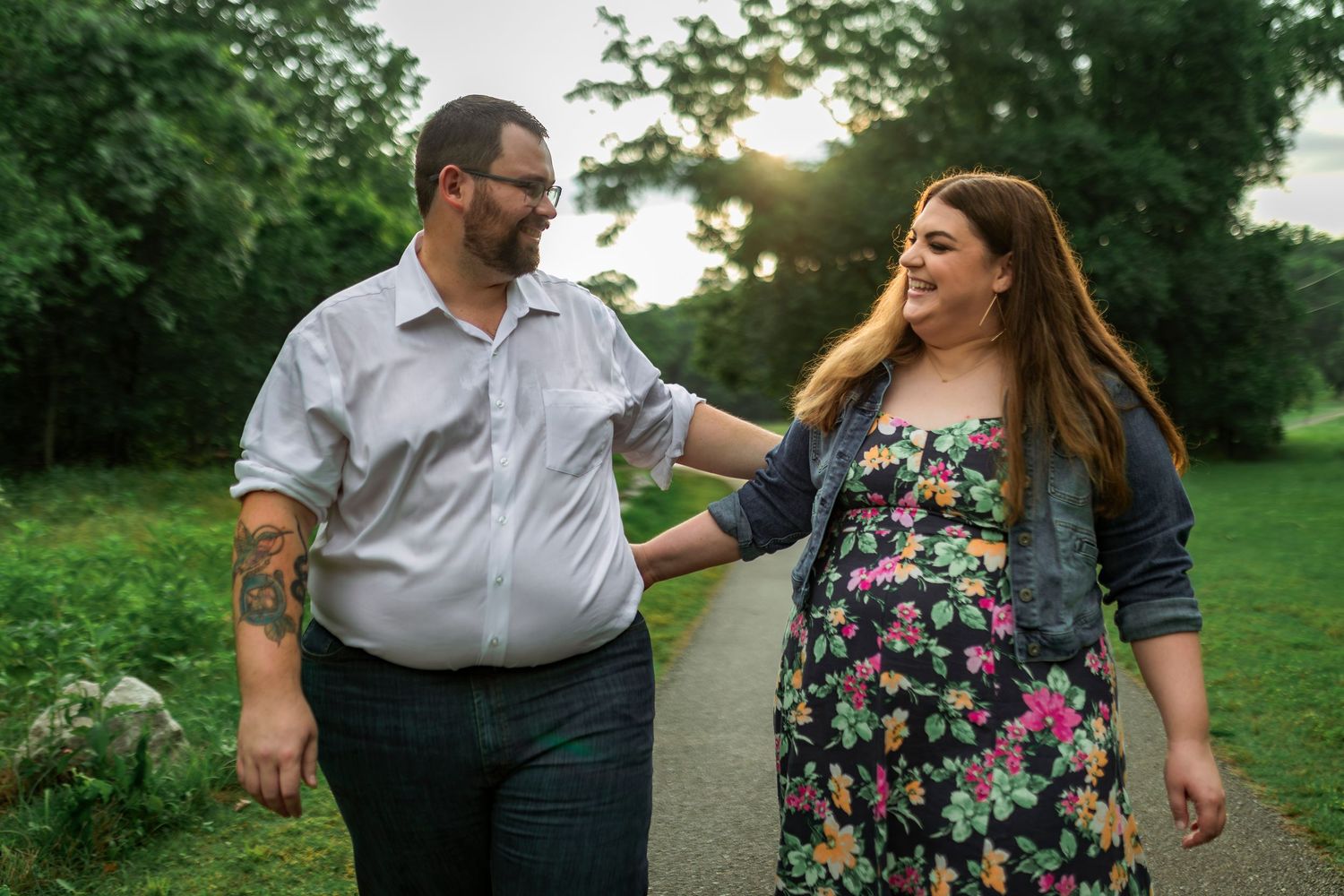 A couple walking together in a garden setting during sunset with greenery in the background.
