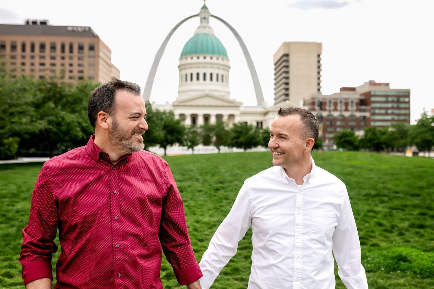 Gay couple holding hands and smiling during engagement session in St Louis Missouri.