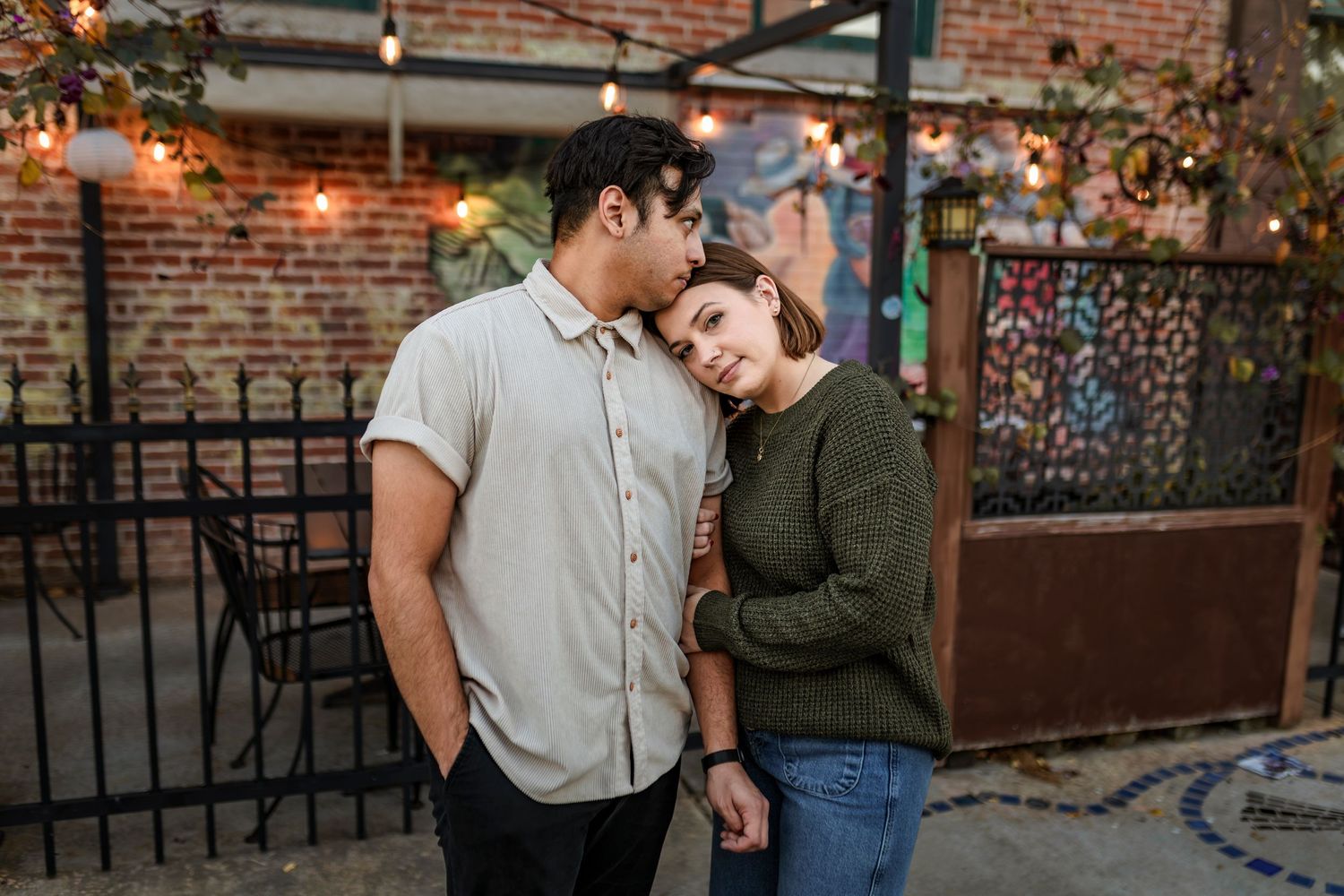 Intimate portrait of couple embracing against rustic brick wall backdrop at Cusco Cafe in Downtown Springfield MO.