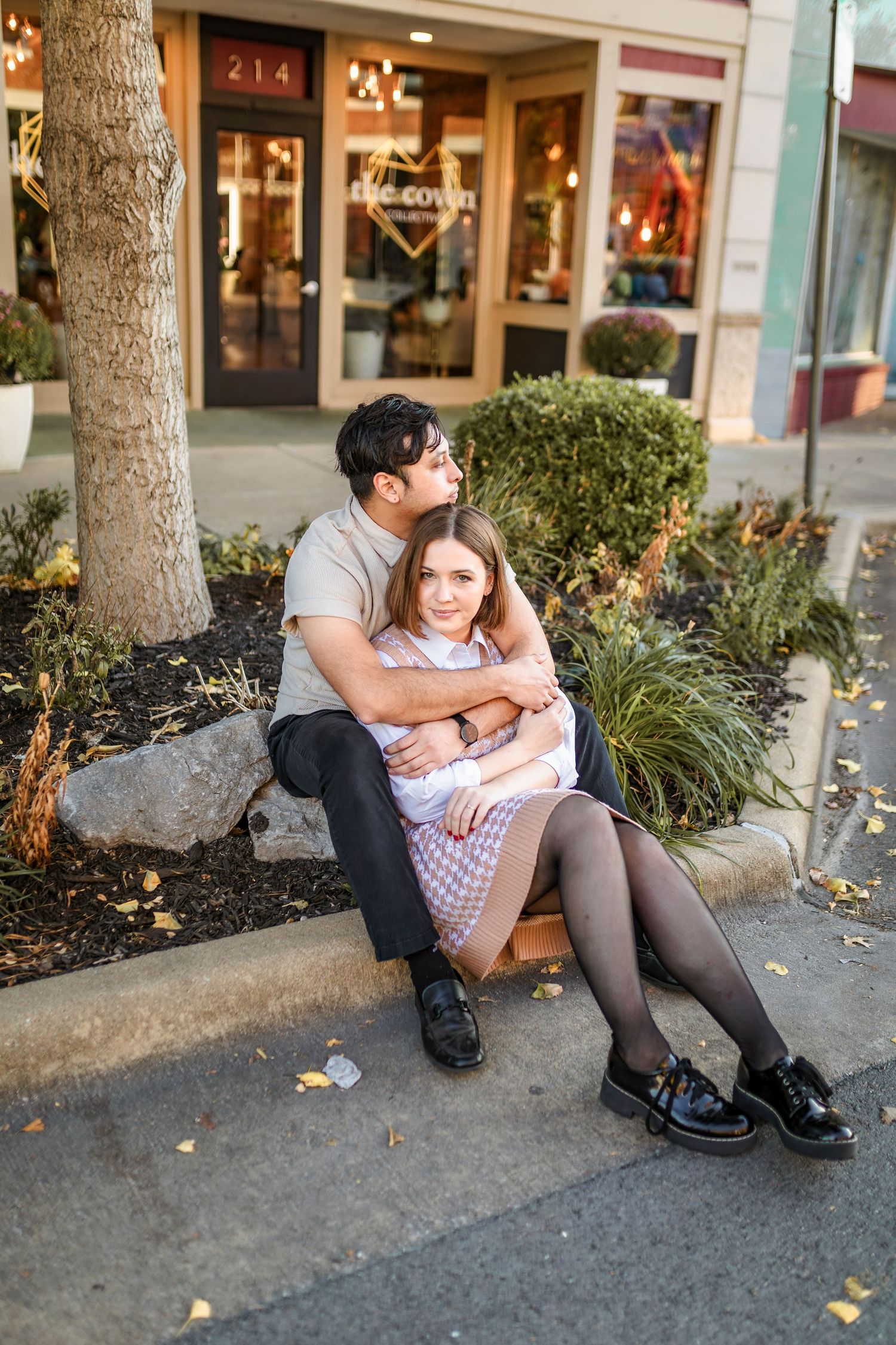 Couple sitting together on a curb outside a Commercial St Springfield Missouri storefront with garden landscaping.