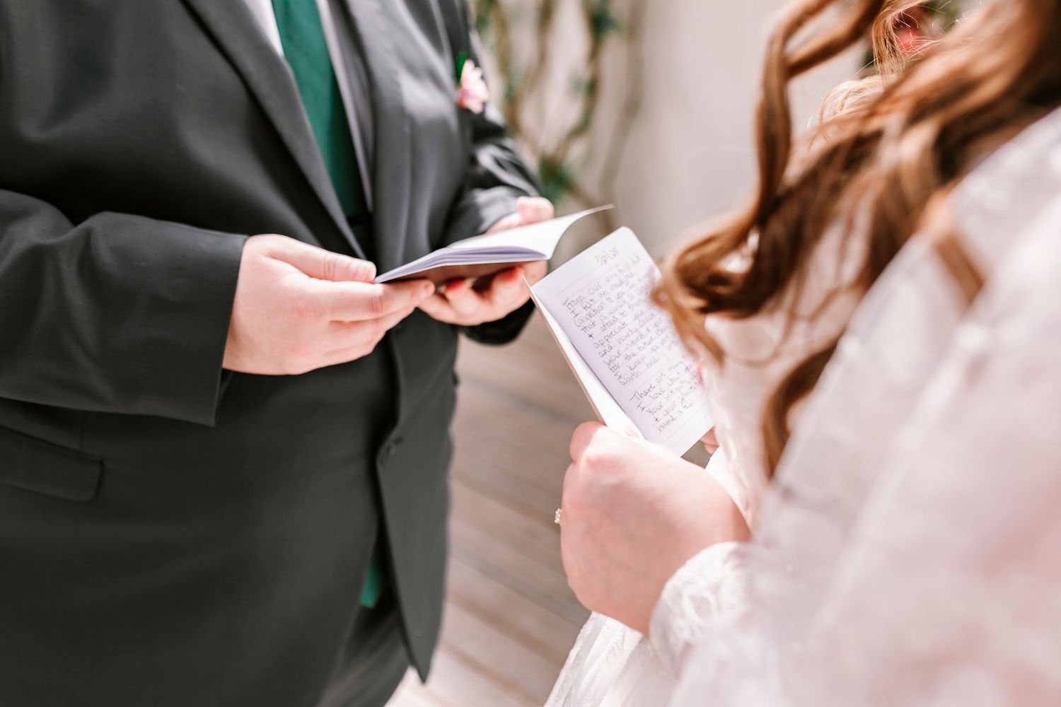 Two people exchanging wedding vows from paper documents at an intimate ceremony.