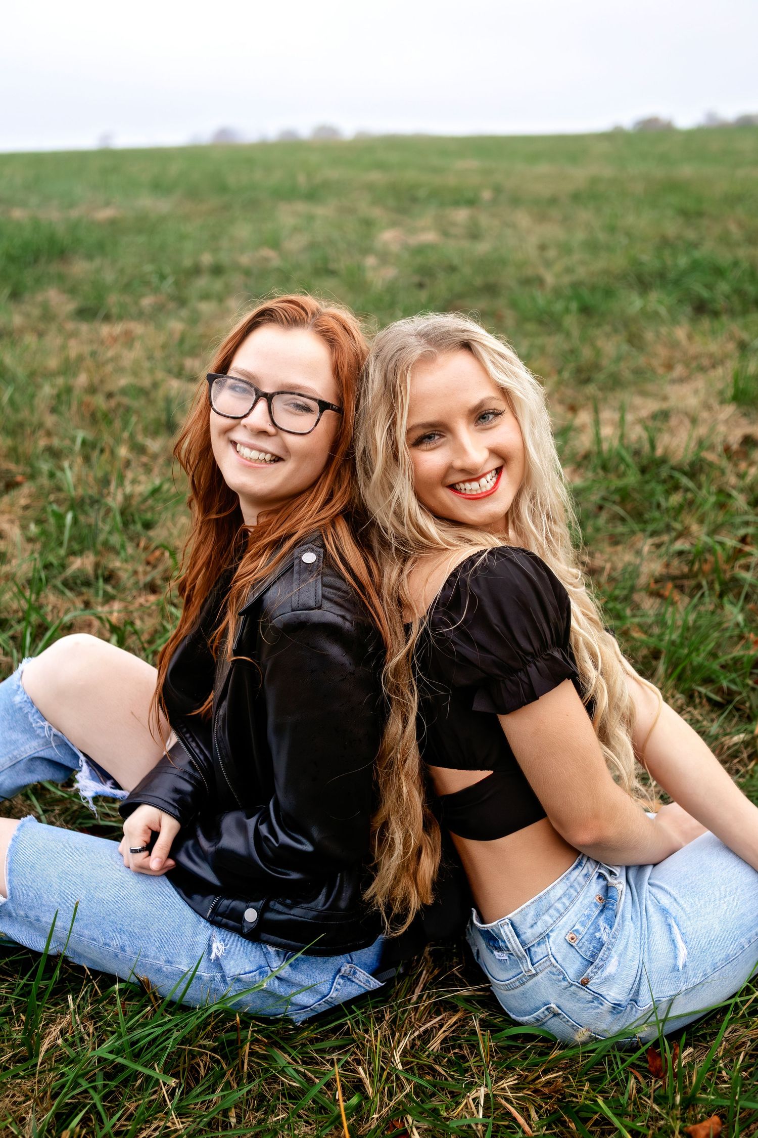 Two friends lying in green grass pose casually for a series of playful photos on a sunny day at Fellows Lake Springfield MO.