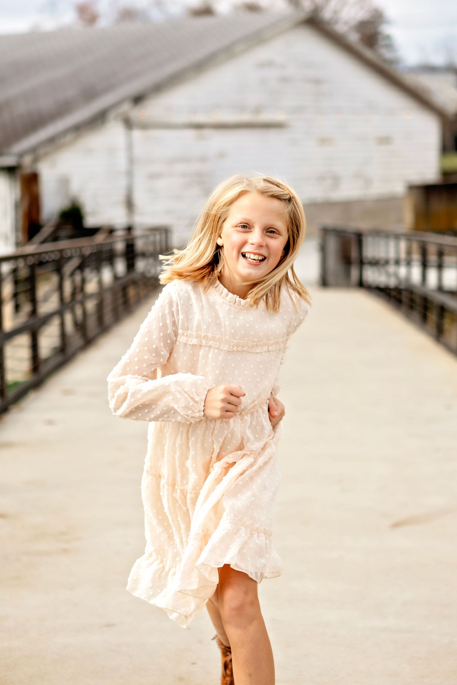 Dancing in a peach lace dress on a wooden boardwalk, a joyful soul spins with carefree delight on a sunny day.