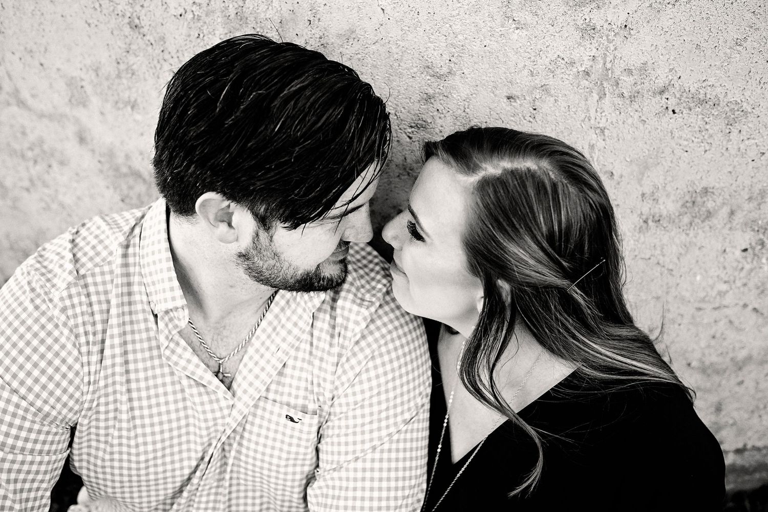Black and white artistic photo sequence shows couple sharing intimate romantic moments against textured wall background.