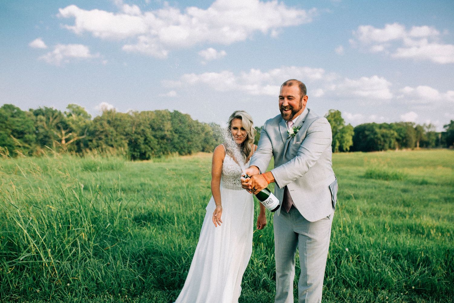Happy couple celebrates in sunny meadow with bright summer flowers.