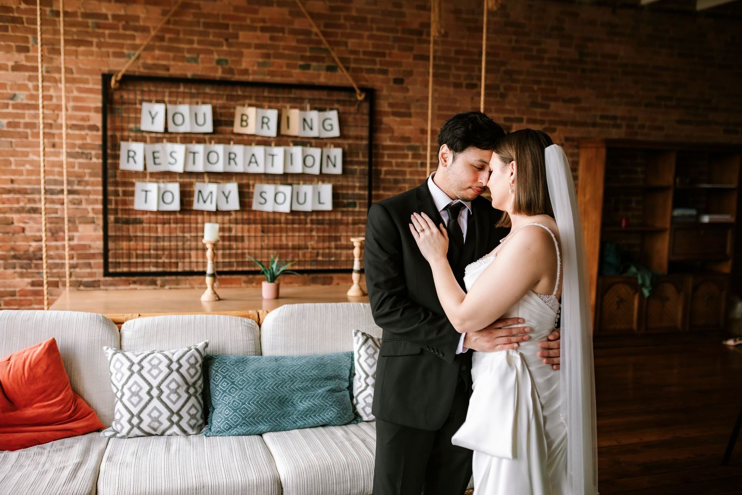 A romantic couple embrace in front of an exposed brick wall in a Springfield MO downtown AirBnb just before their wedding.