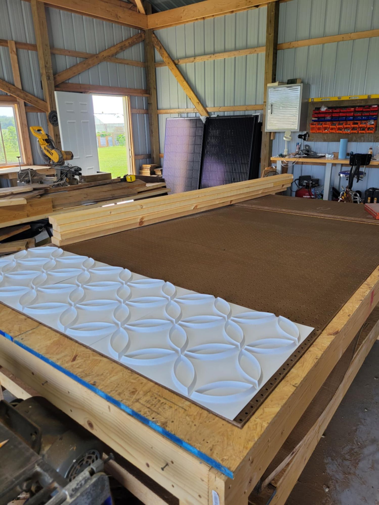 3D wall panel mold with decorative floral pattern lies on wooden workbench next to brown surface in workshop setting.