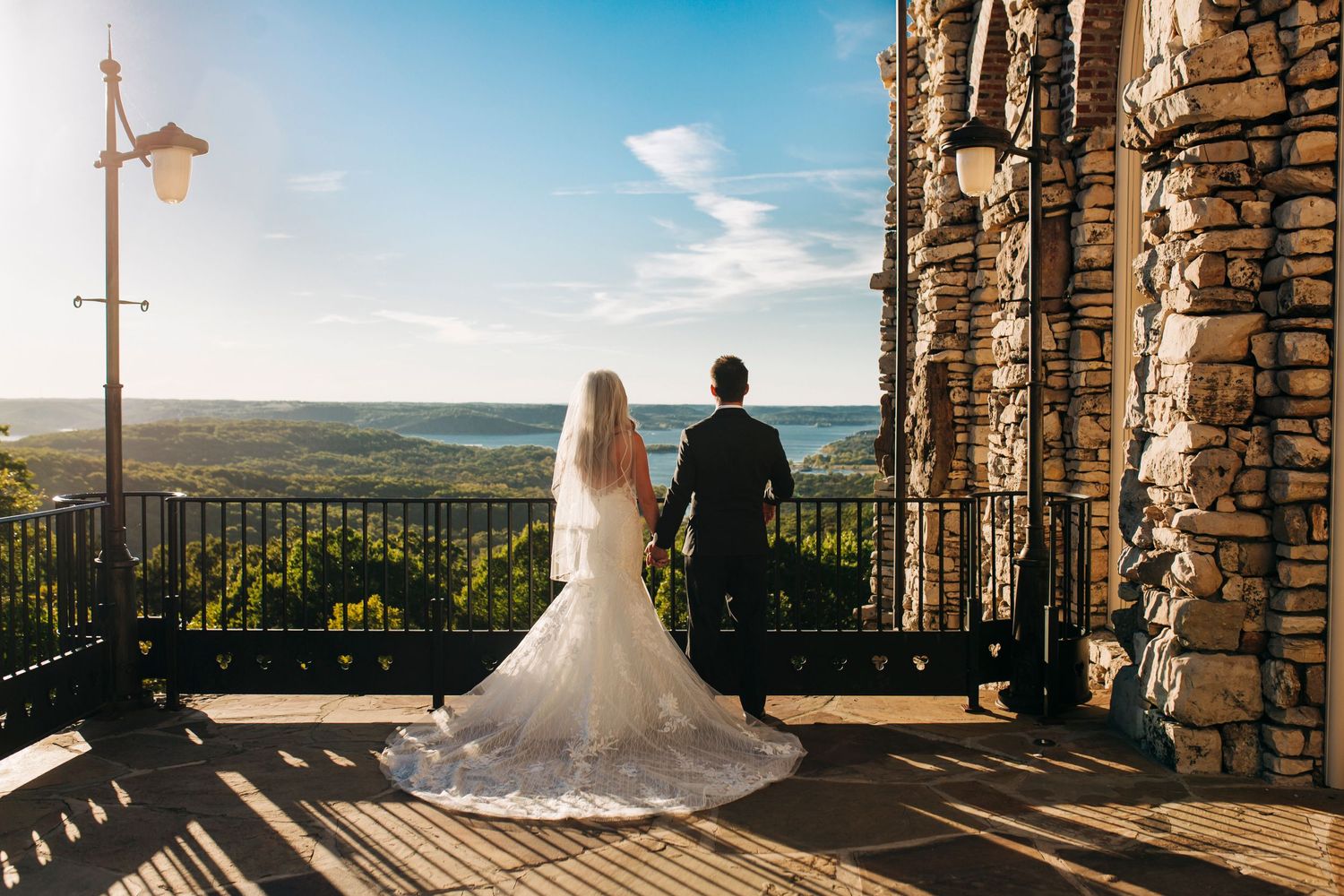 Silhouetted couple admires scenic mountain view from stone balcony overlook at Top of the Rock Chapel in Branson Missouri.