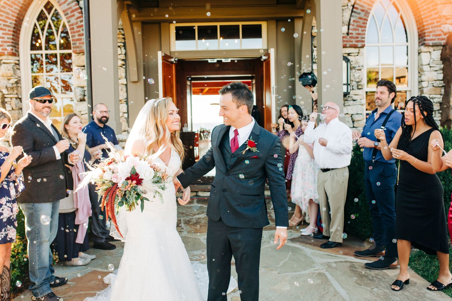 Couple celebrates during wedding recessional while guests line church entrance pathway.