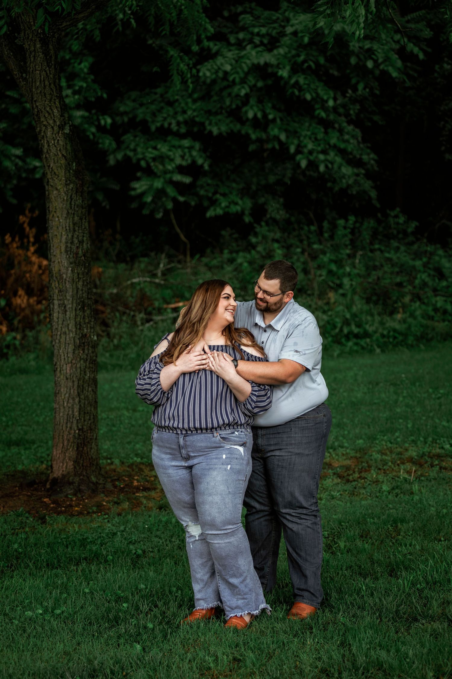 A couple enjoying a romantic moment while dancing together in a lush green park setting.