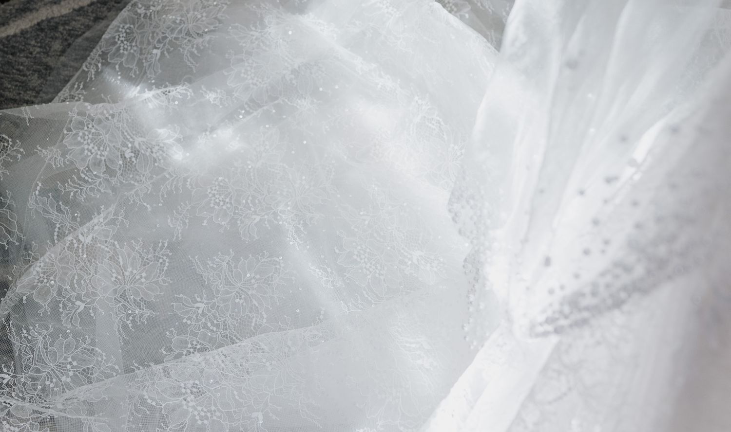 Close-up detail of shimmering white bridal veil fabric with delicate beading and texture.