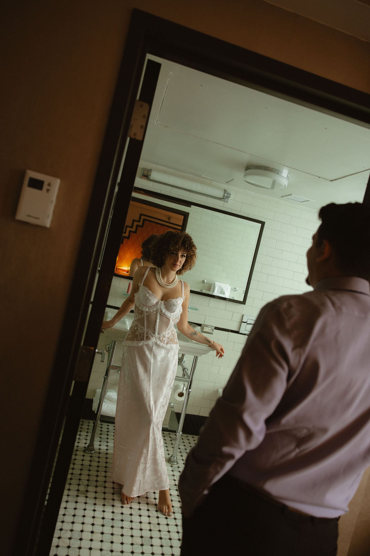 Couple getting ready in a vintage-style bathroom with black and white tile floor.