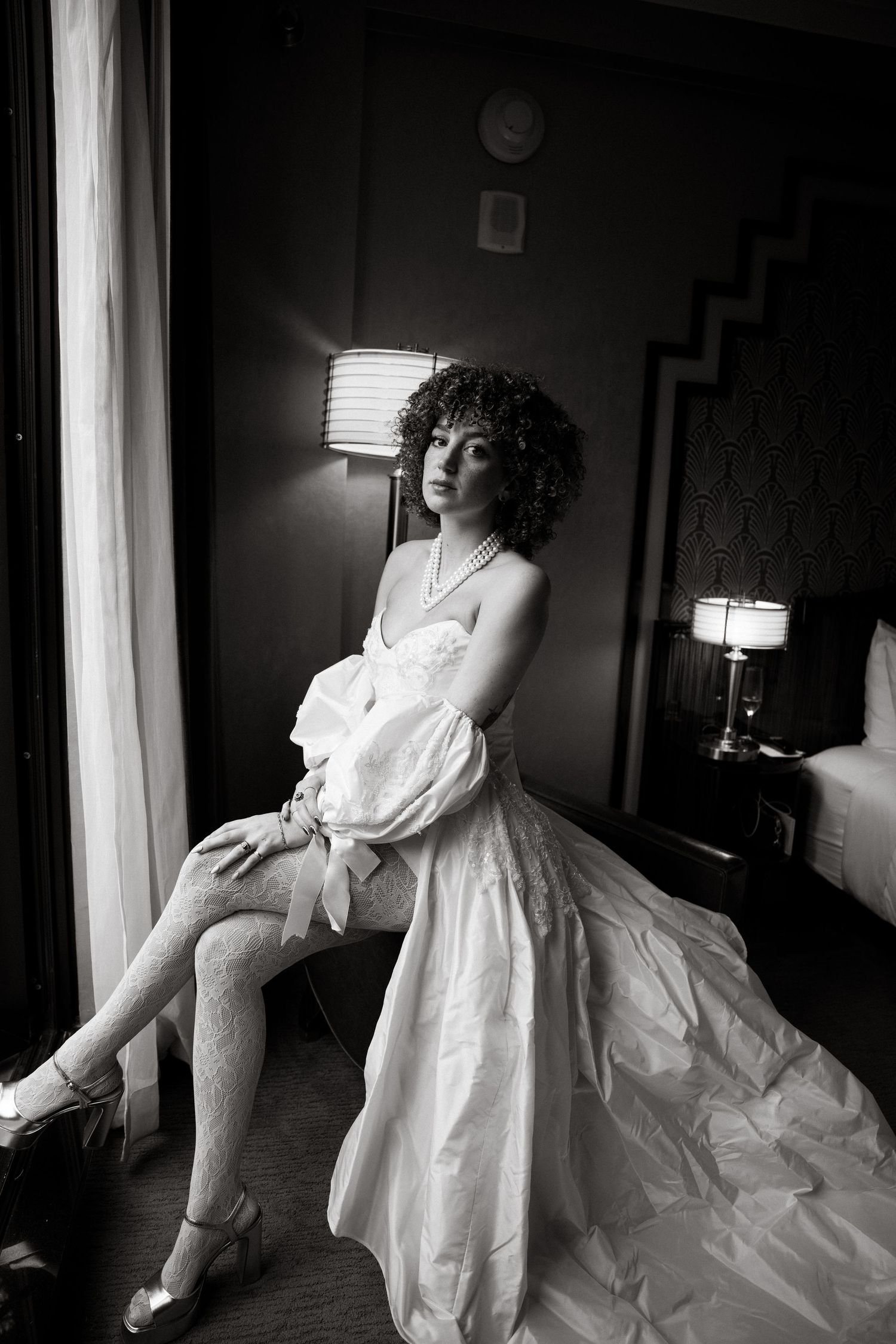 Artistic black and white boudoir photos in a hotel room with dramatic lighting.